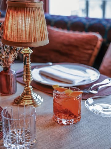a table with a glass of liquid and a lamp