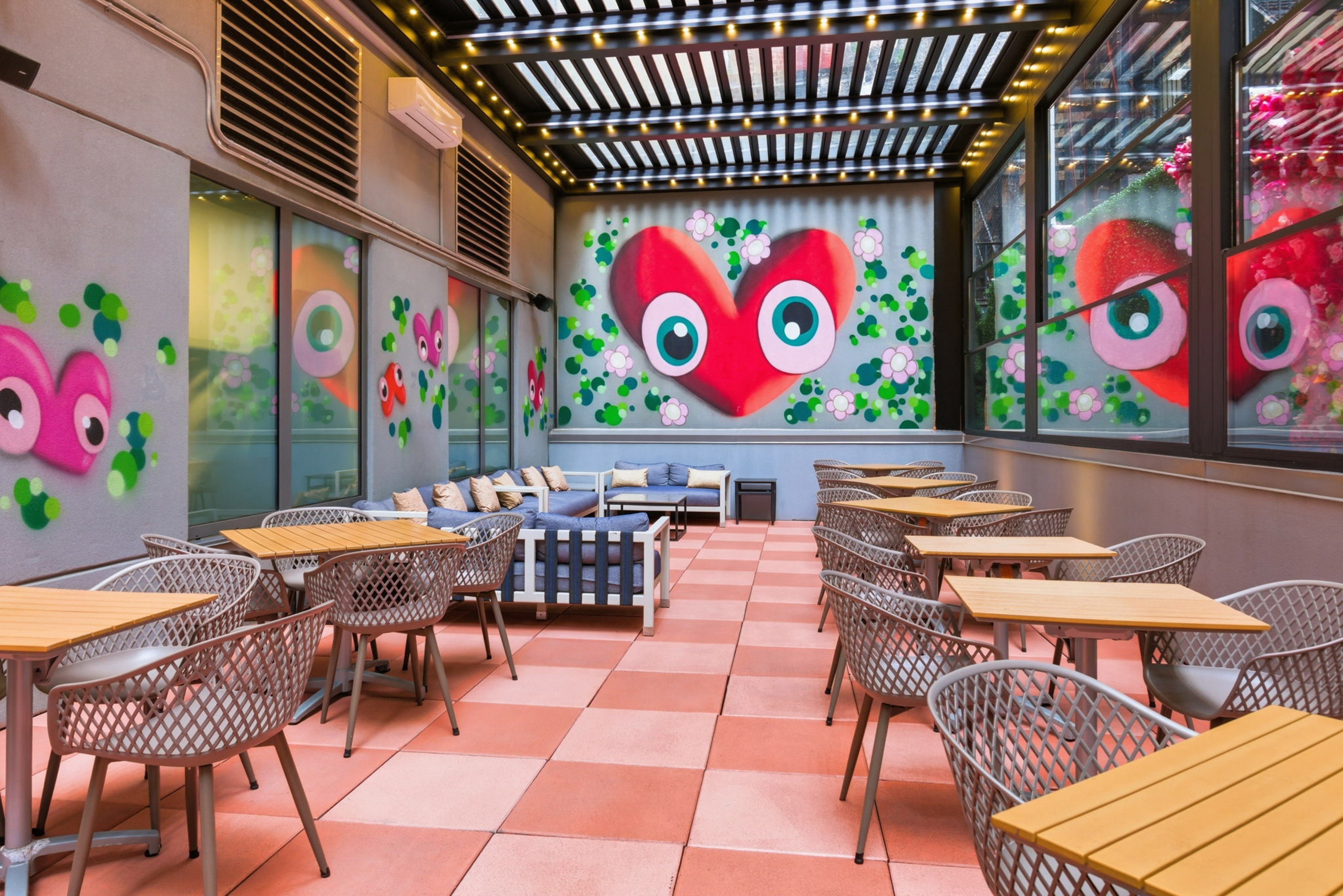 Outdoor restaurant patio with colorful heart mural and varied seating.