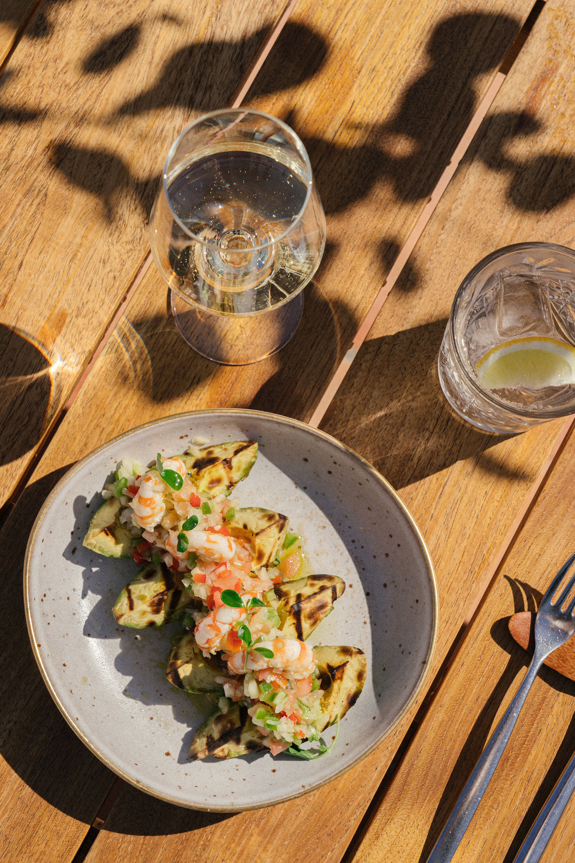 Sunny grilled avocado with shrimp ceviche, sparkling wine, outdoor dining.