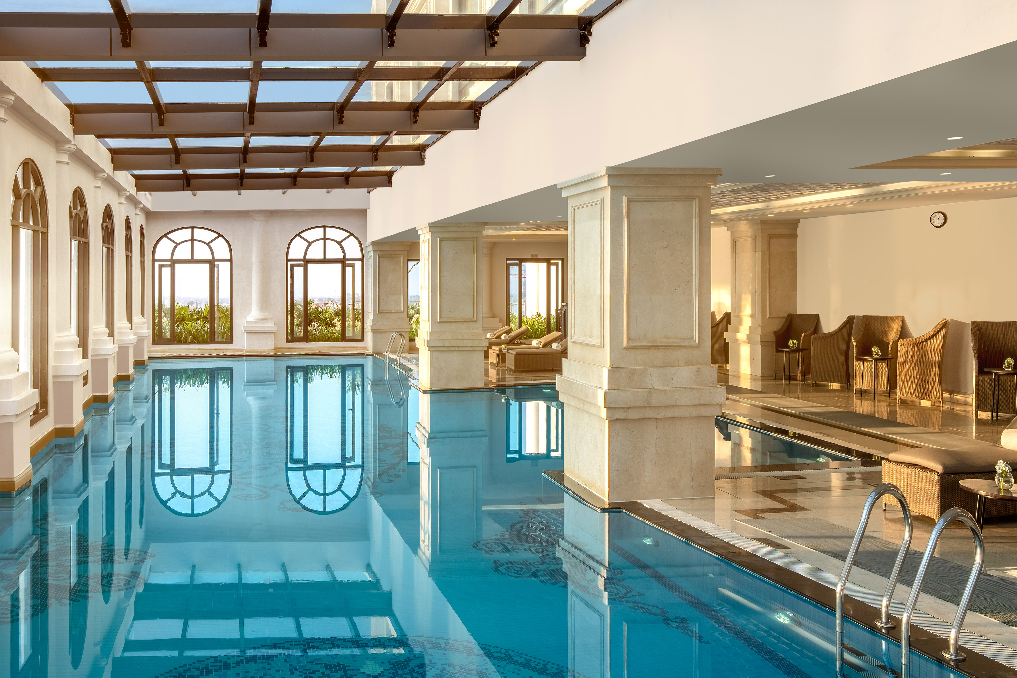 Luxury indoor swimming pool with architectural columns and skylight.