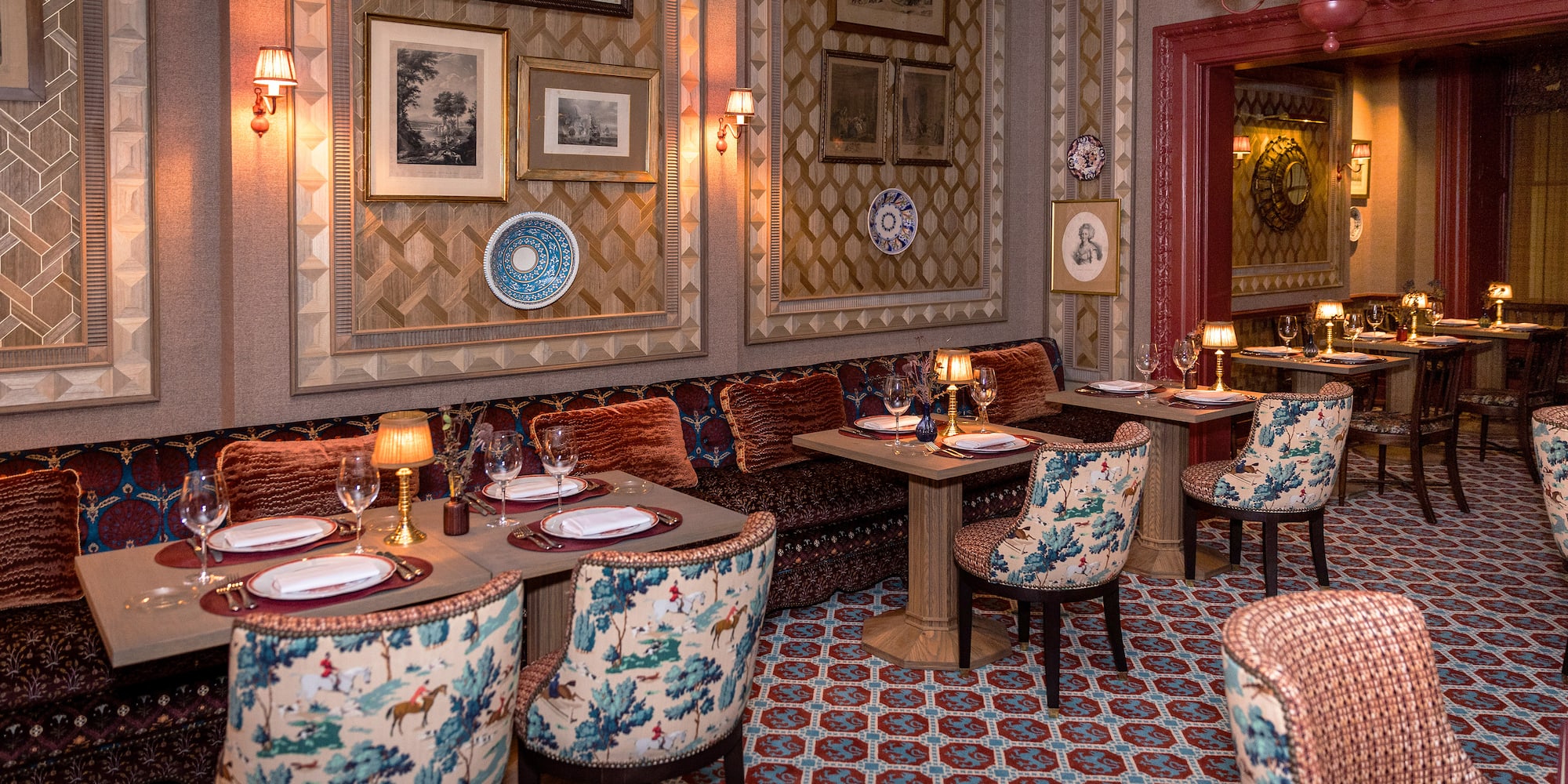 Luxurious restaurant interior with toile upholstered chairs and patterned walls.