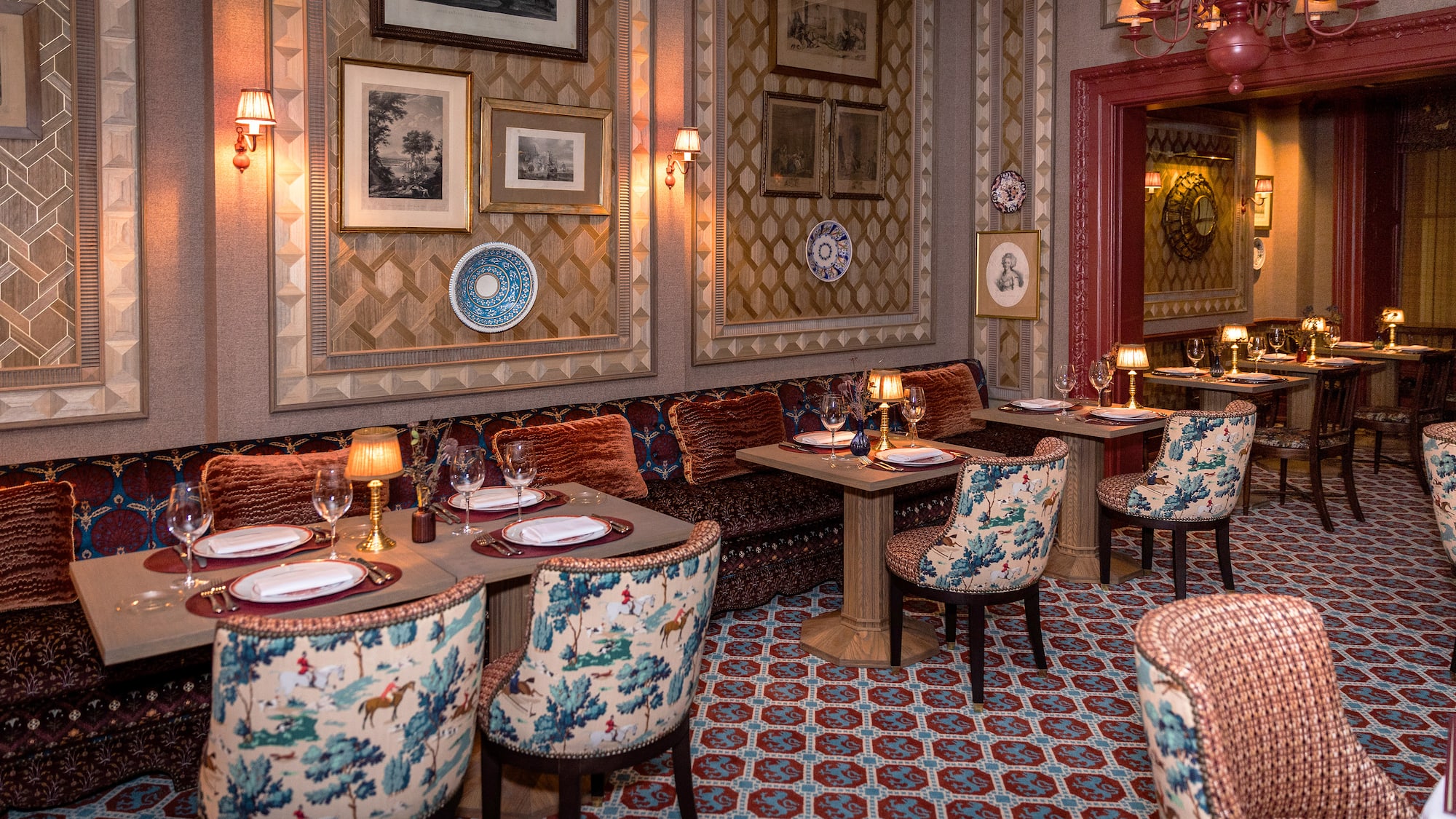 Luxurious restaurant interior with toile upholstered chairs and patterned walls.