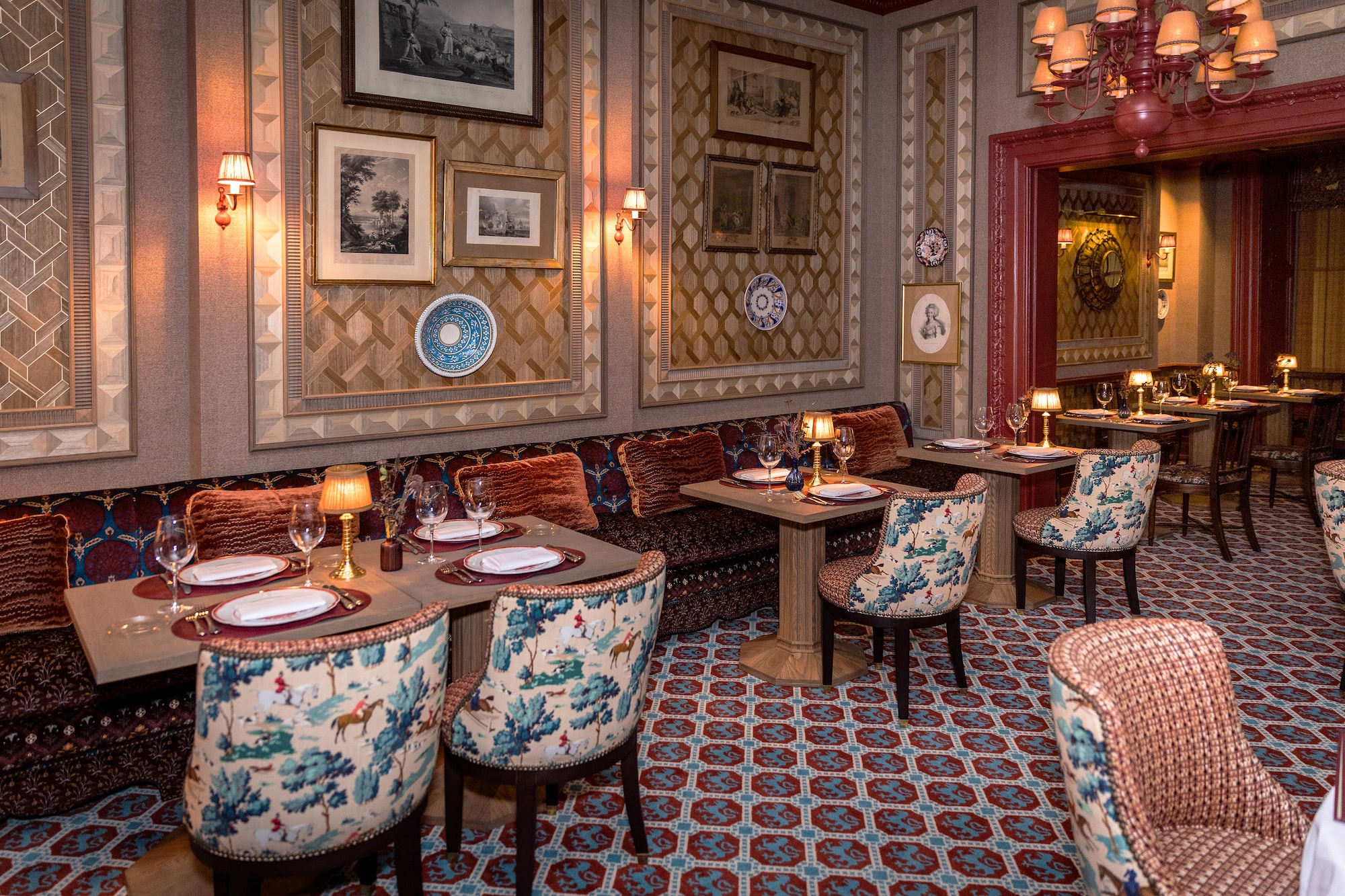 Luxurious restaurant interior with toile upholstered chairs and patterned walls.