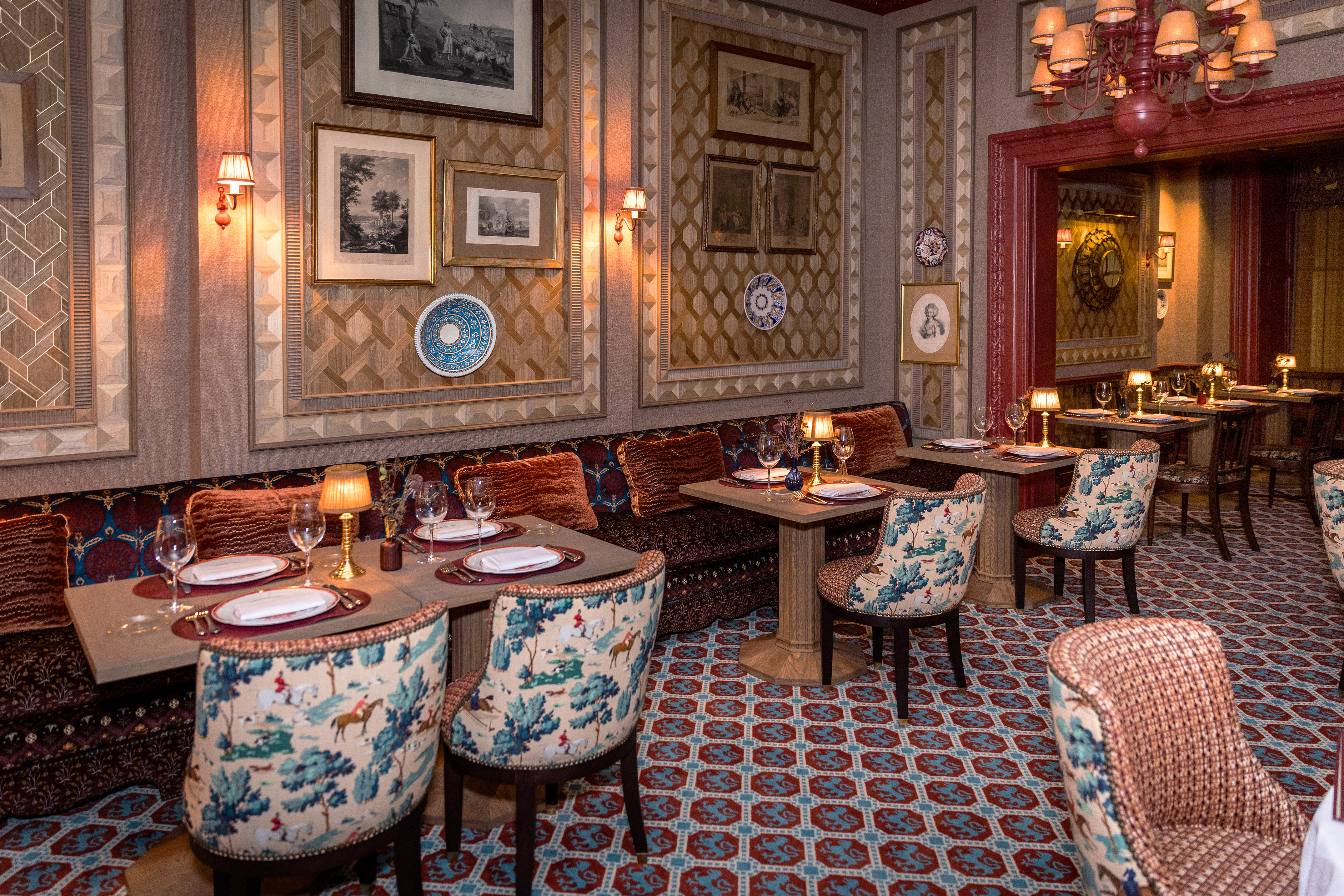 Luxurious restaurant interior with toile upholstered chairs and patterned walls.
