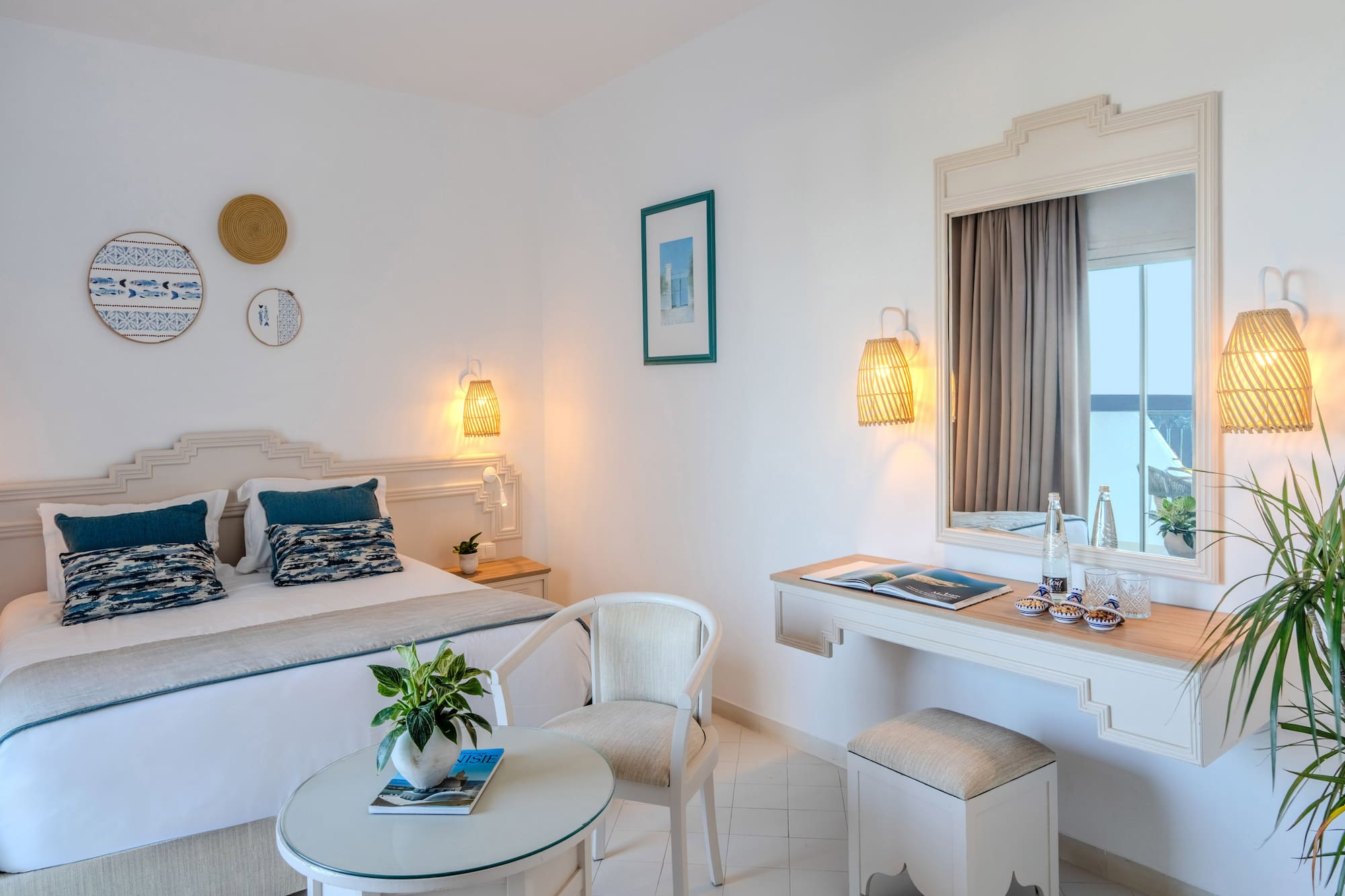 Mediterranean hotel bedroom with white walls, blue accents, and woven decor.
