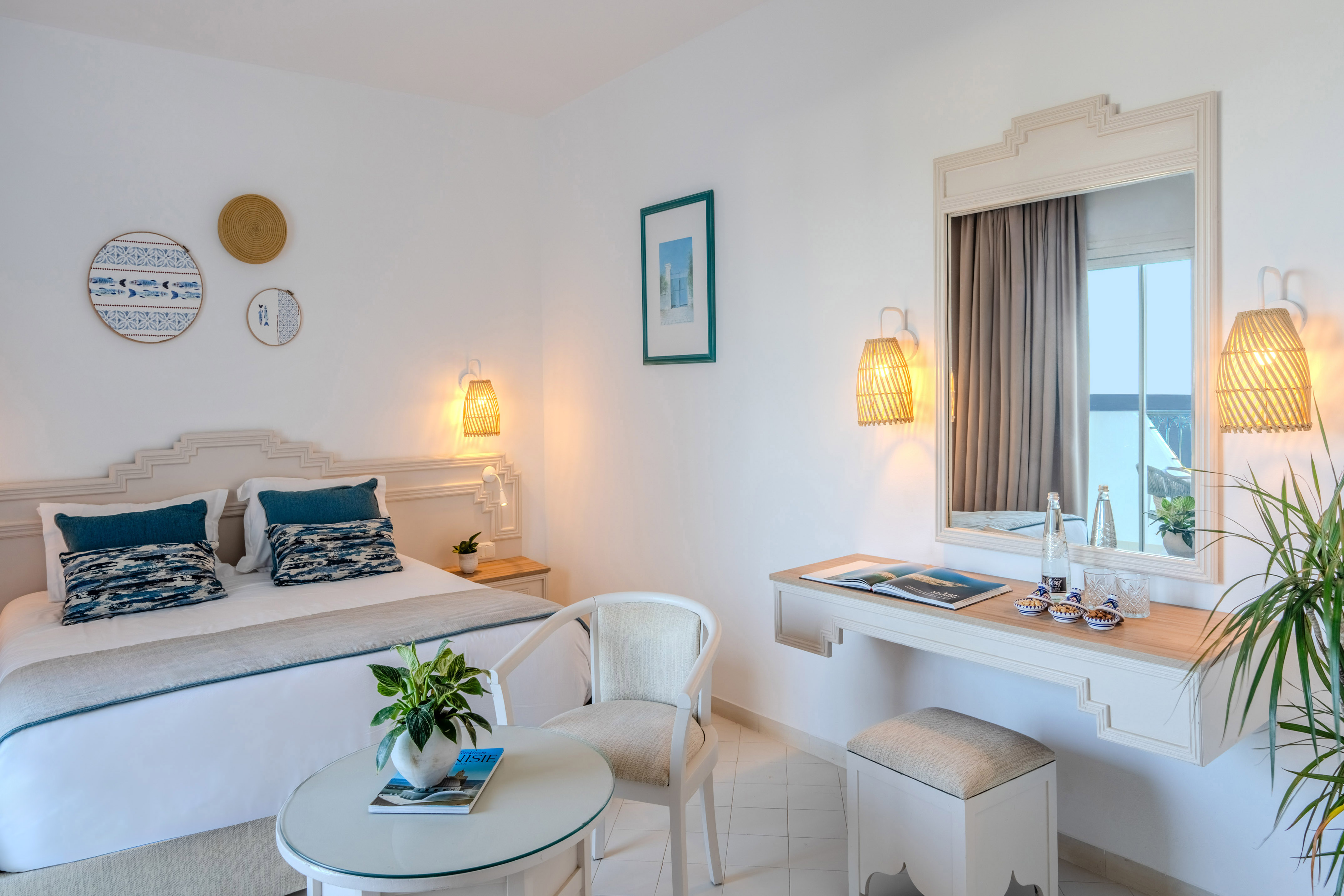 Mediterranean hotel bedroom with white walls, blue accents, and woven decor.