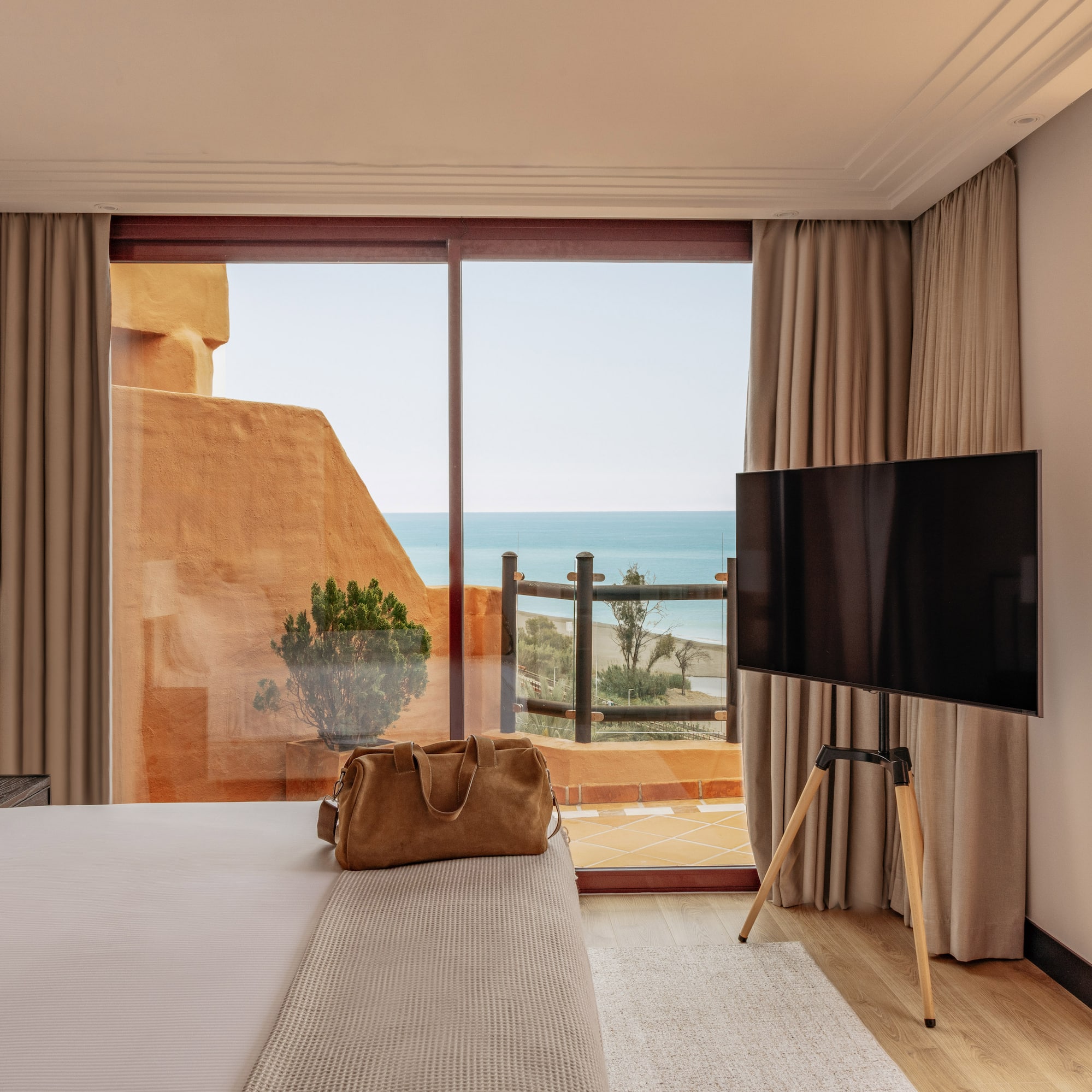Beachfront hotel room featuring a bed, TV, and balcony with sea views.