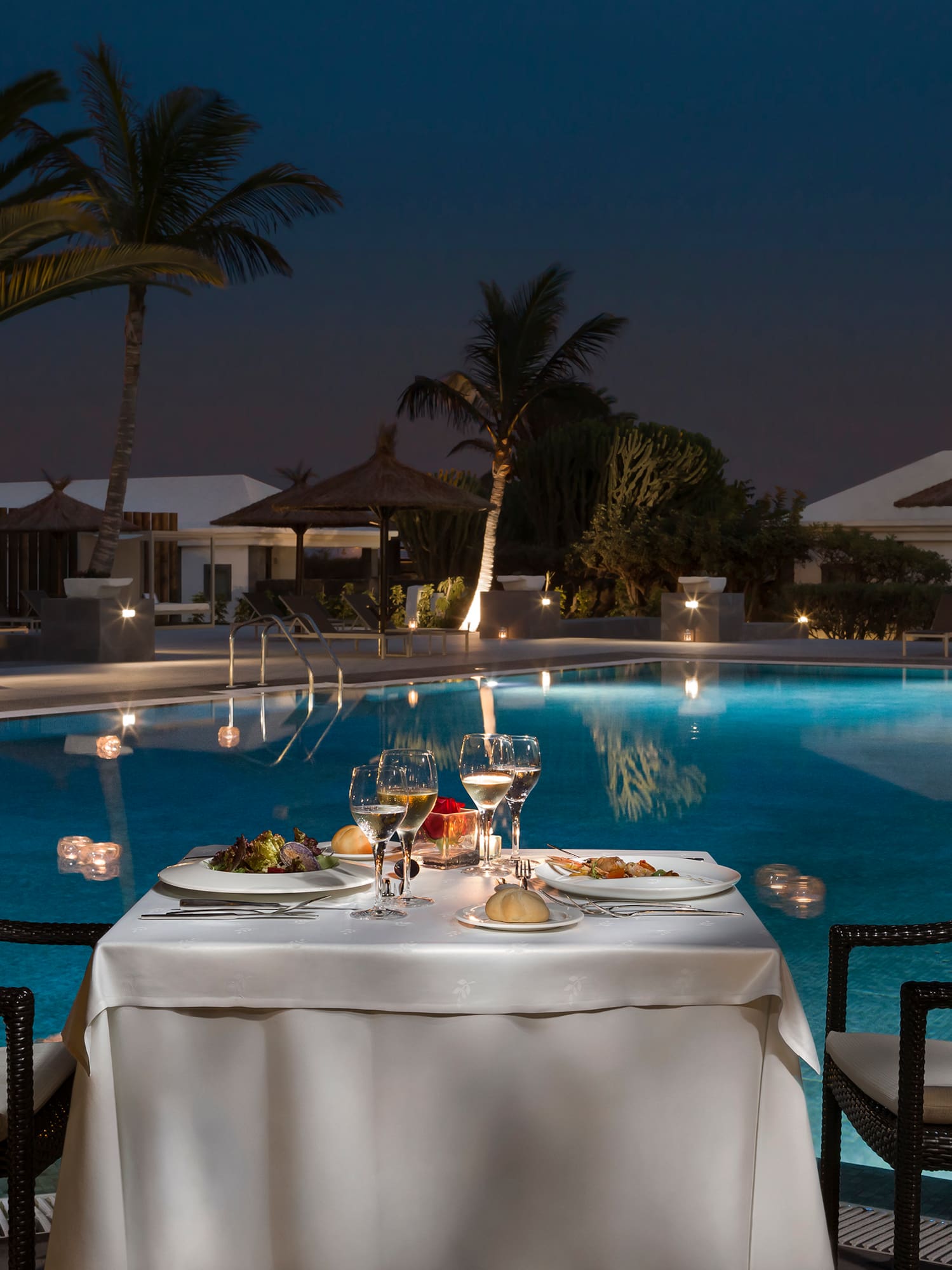 a table with food and drinks on it by a pool