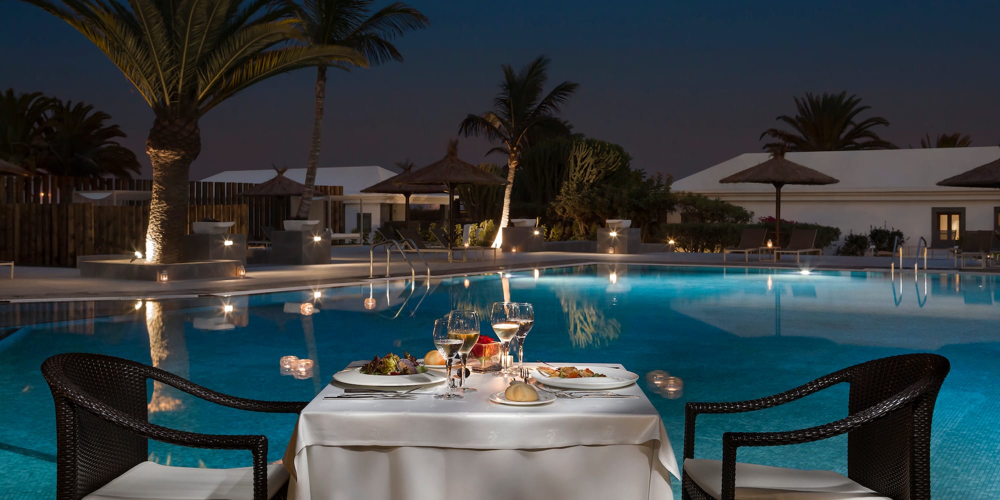 a table with food and drinks on it by a pool