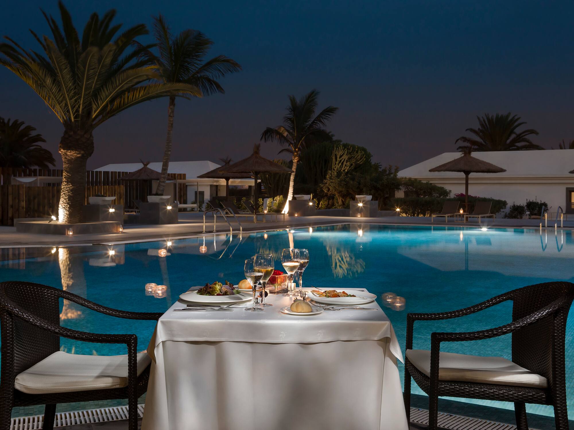 a table with food and drinks on it by a pool