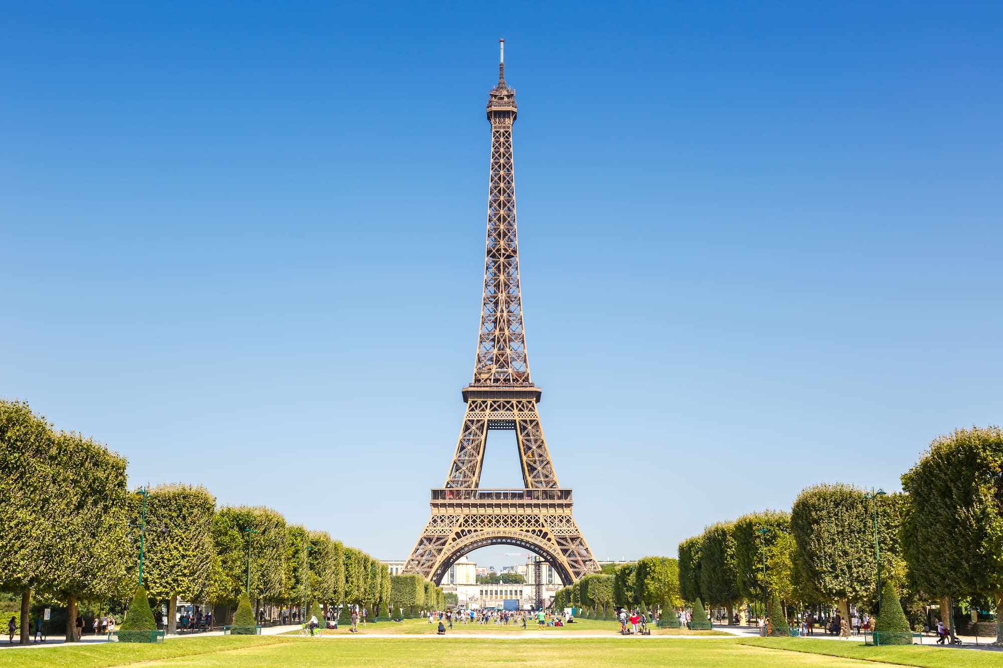 a tall tower with trees and people in the background with Eiffel Tower in the background