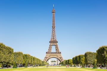 a tall tower with trees and people in the background with Eiffel Tower in the background