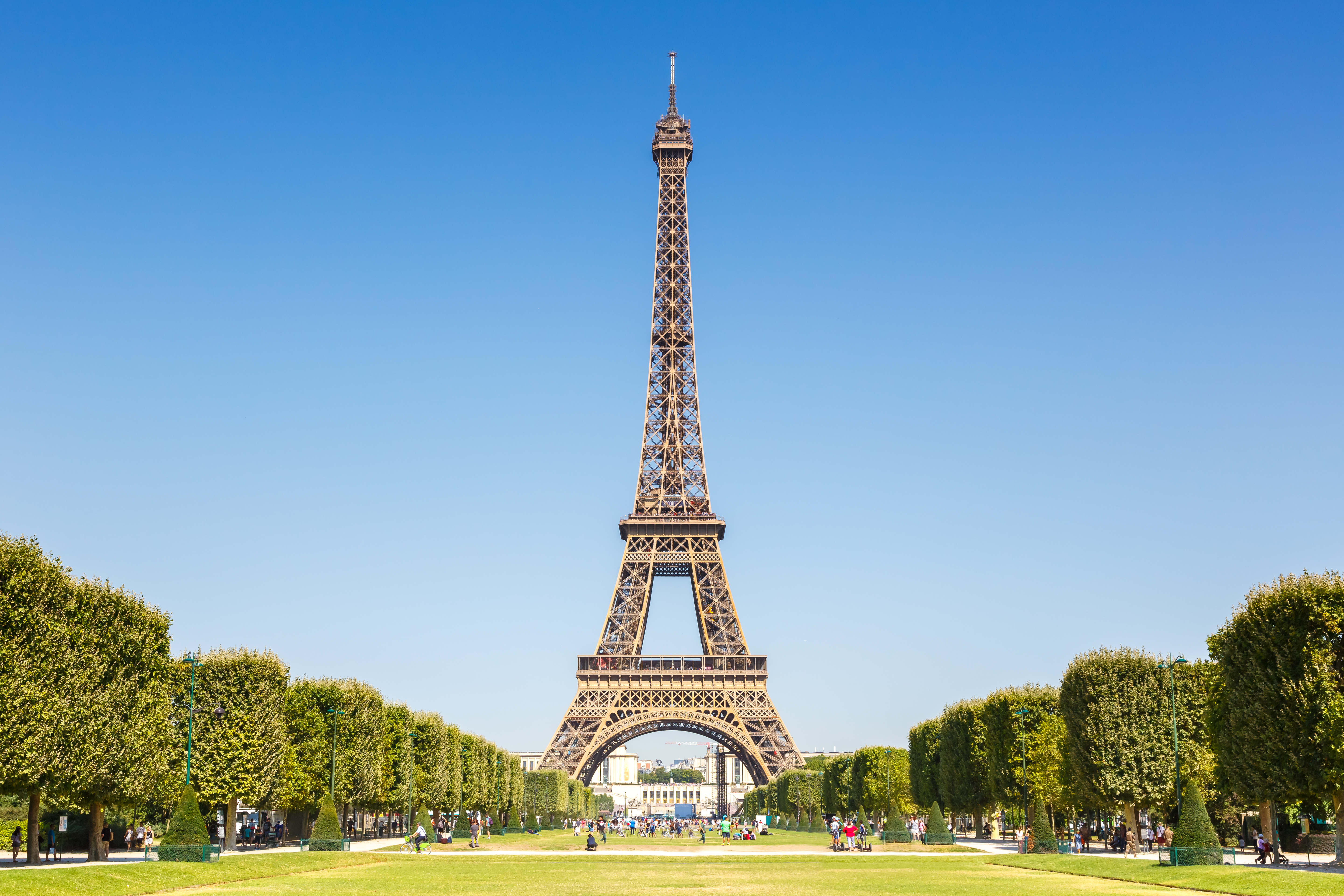 a tall tower with trees and people in the background with Eiffel Tower in the background