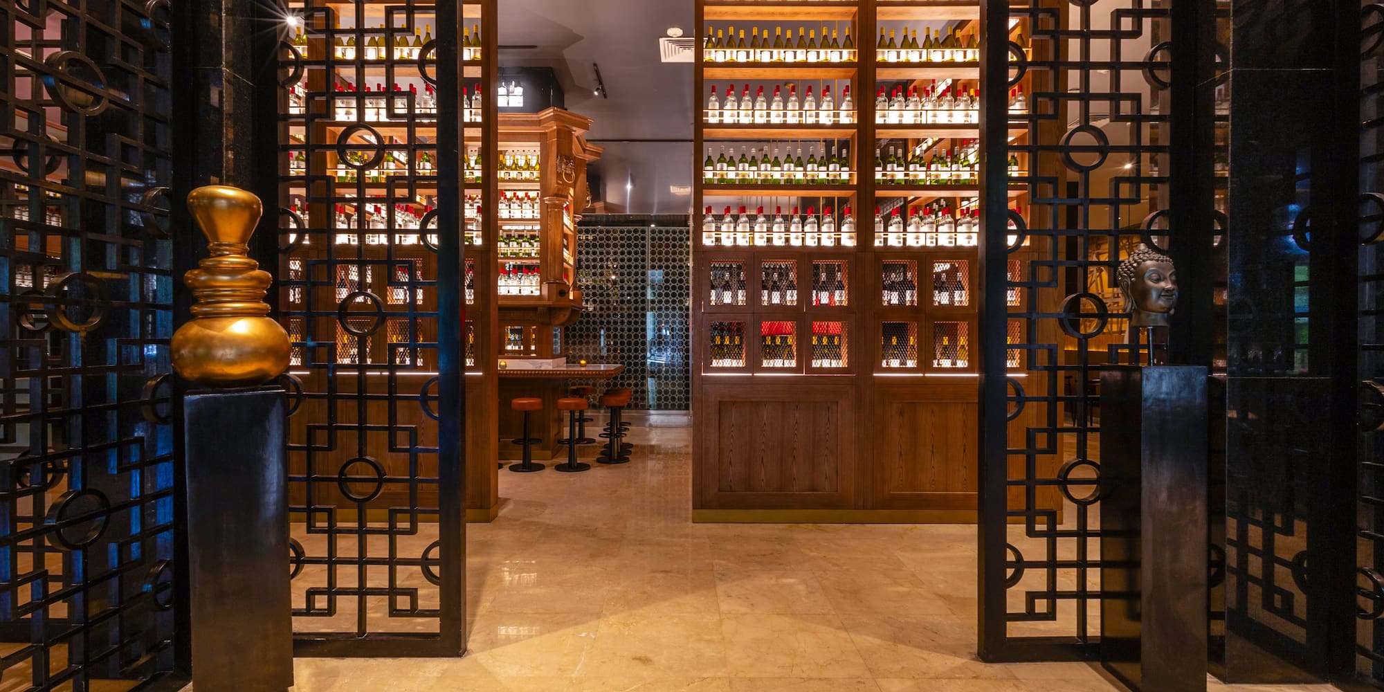 Ornate metal gates to a luxury bar with illuminated liquor bottle shelves.