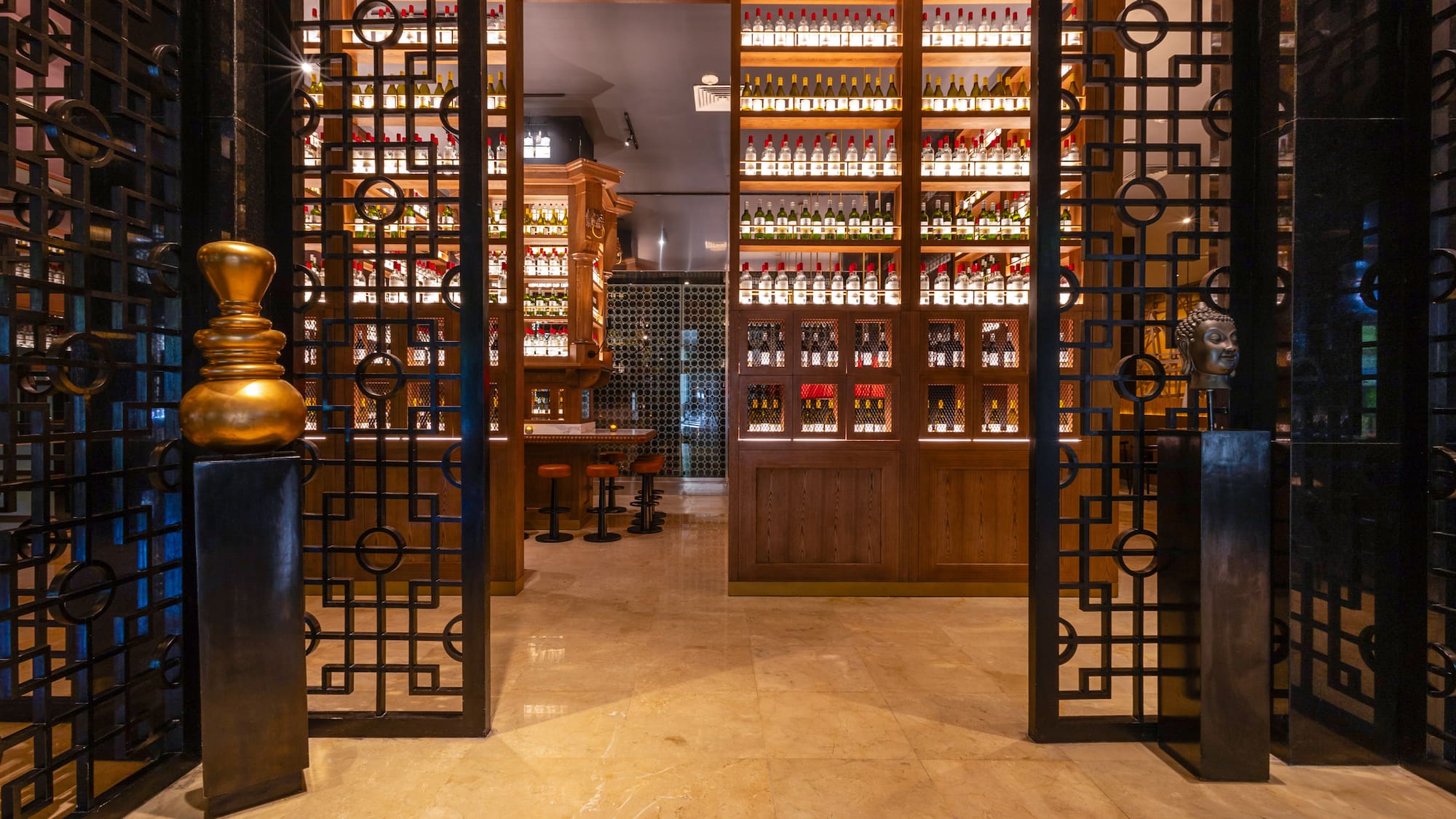 Ornate metal gates to a luxury bar with illuminated liquor bottle shelves.