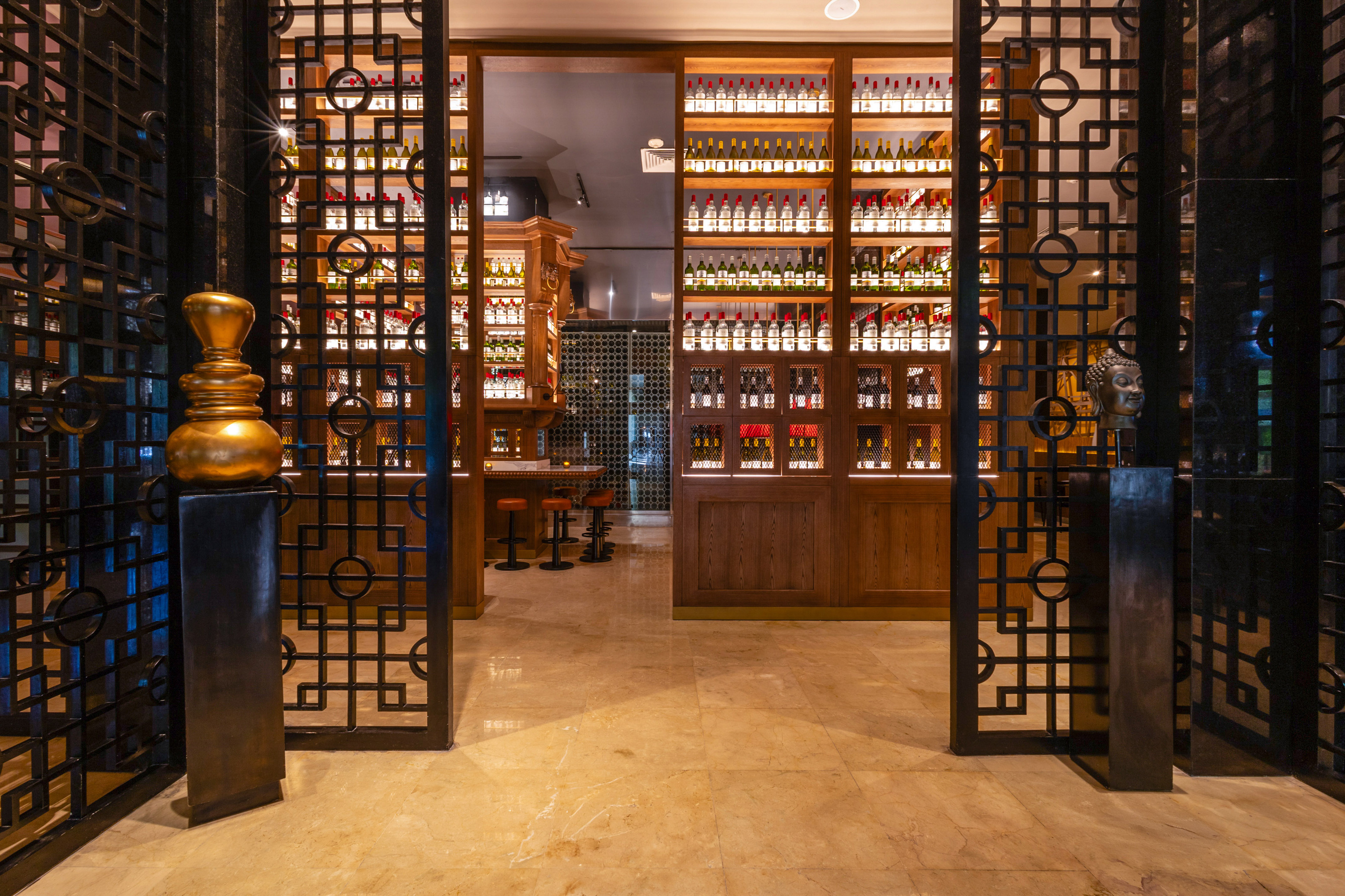 Ornate metal gates to a luxury bar with illuminated liquor bottle shelves.