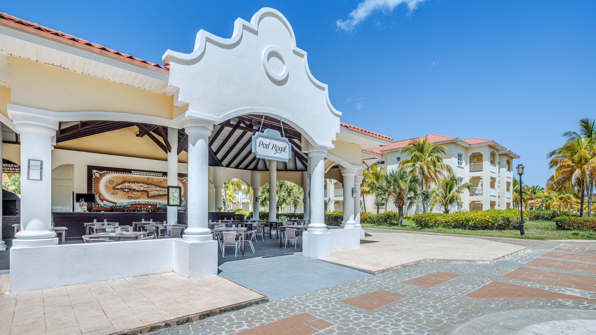a building with a white archway and tables and chairs