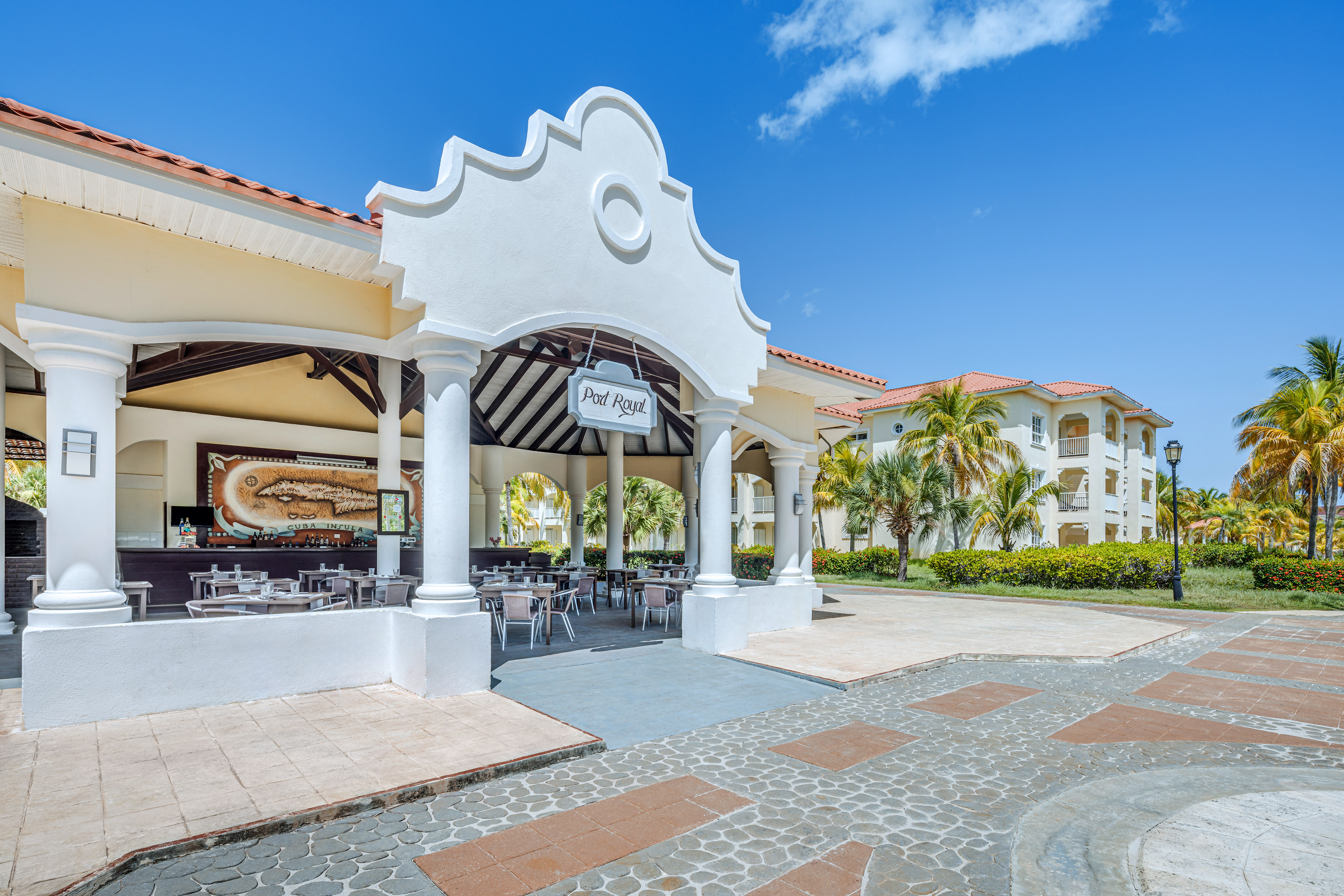 a building with a white archway and tables and chairs