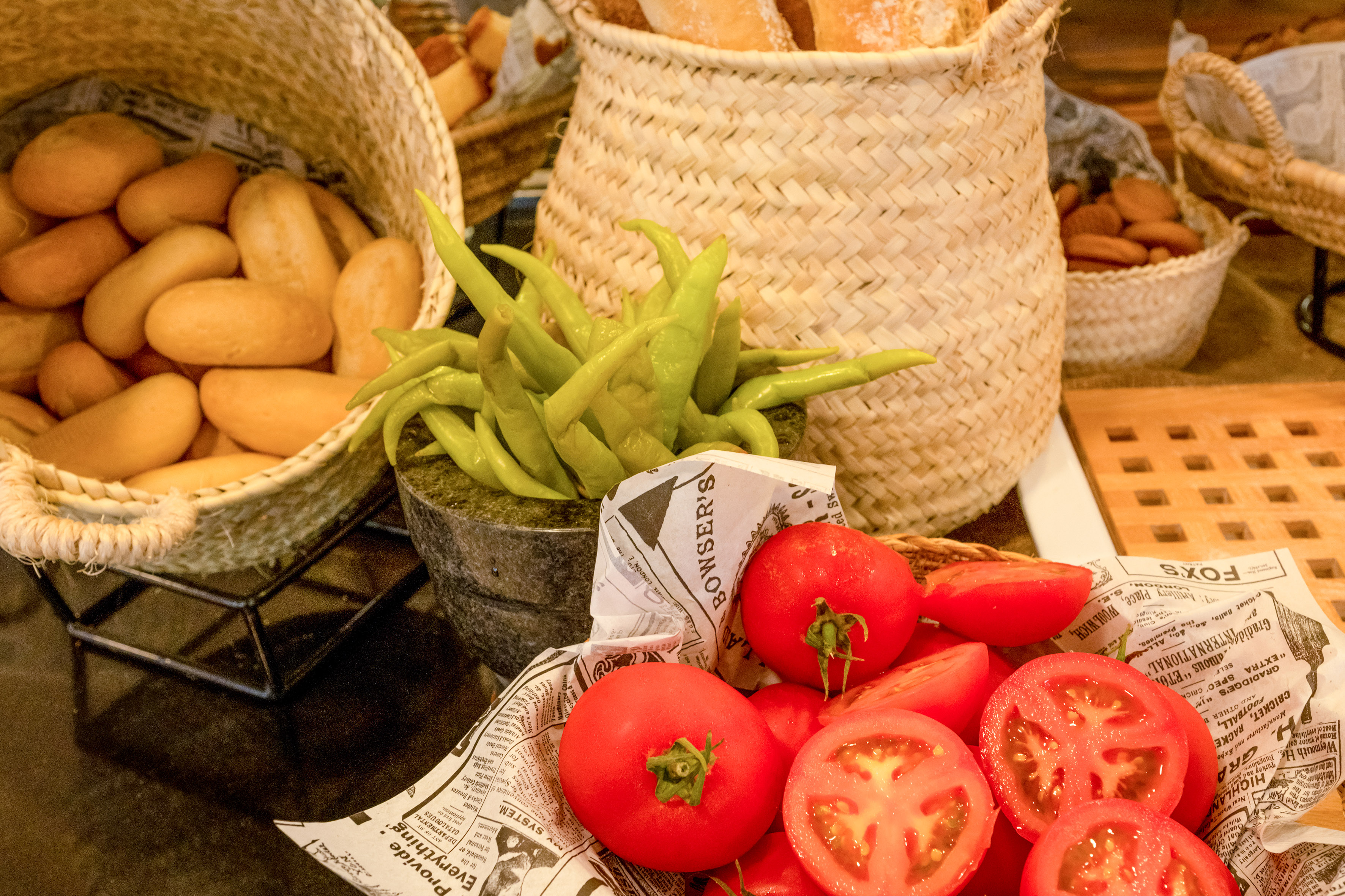 Fresh market produce: tomatoes, green peppers, and bread in wicker baskets.