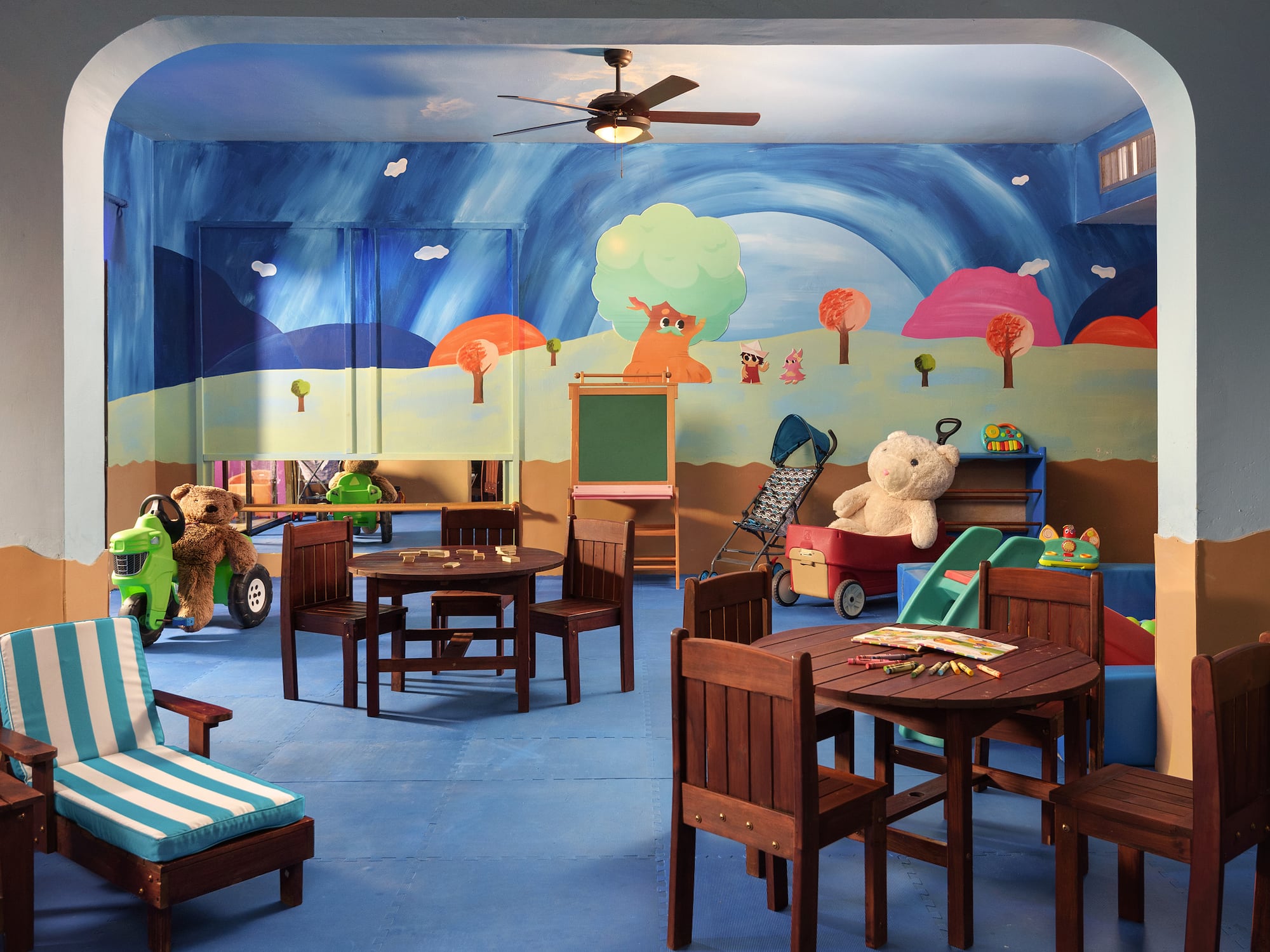 a room with a mural of a cartoon landscape and a table and chairs