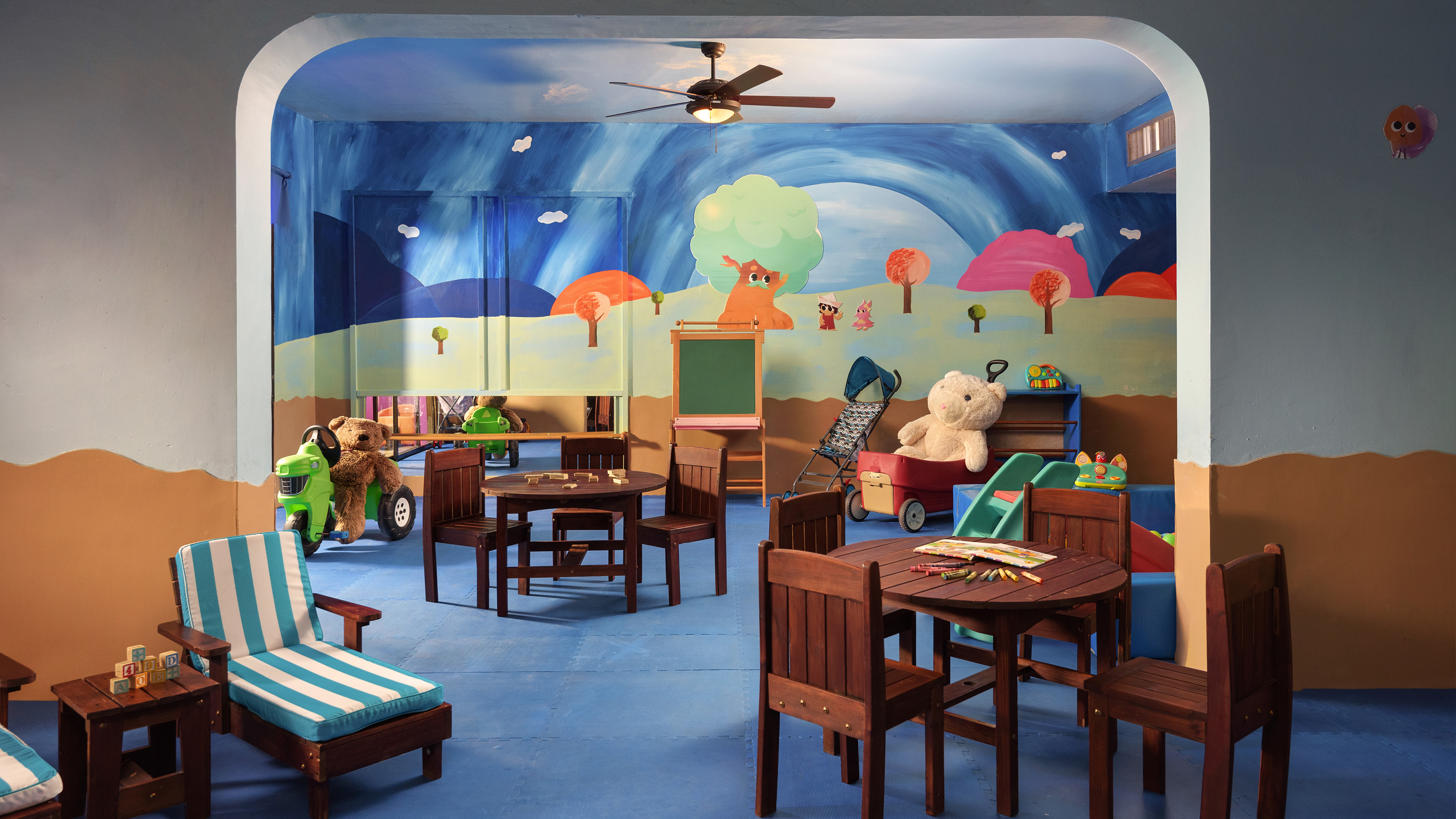Vibrant kids playroom with colorful cartoon murals, child-sized furniture, and various toys.