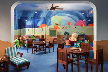 a room with a mural of a cartoon landscape and a table and chairs