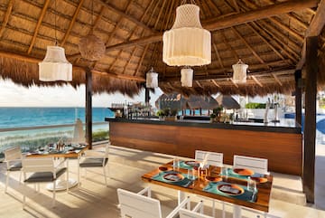 a restaurant with a thatched roof and a beach view