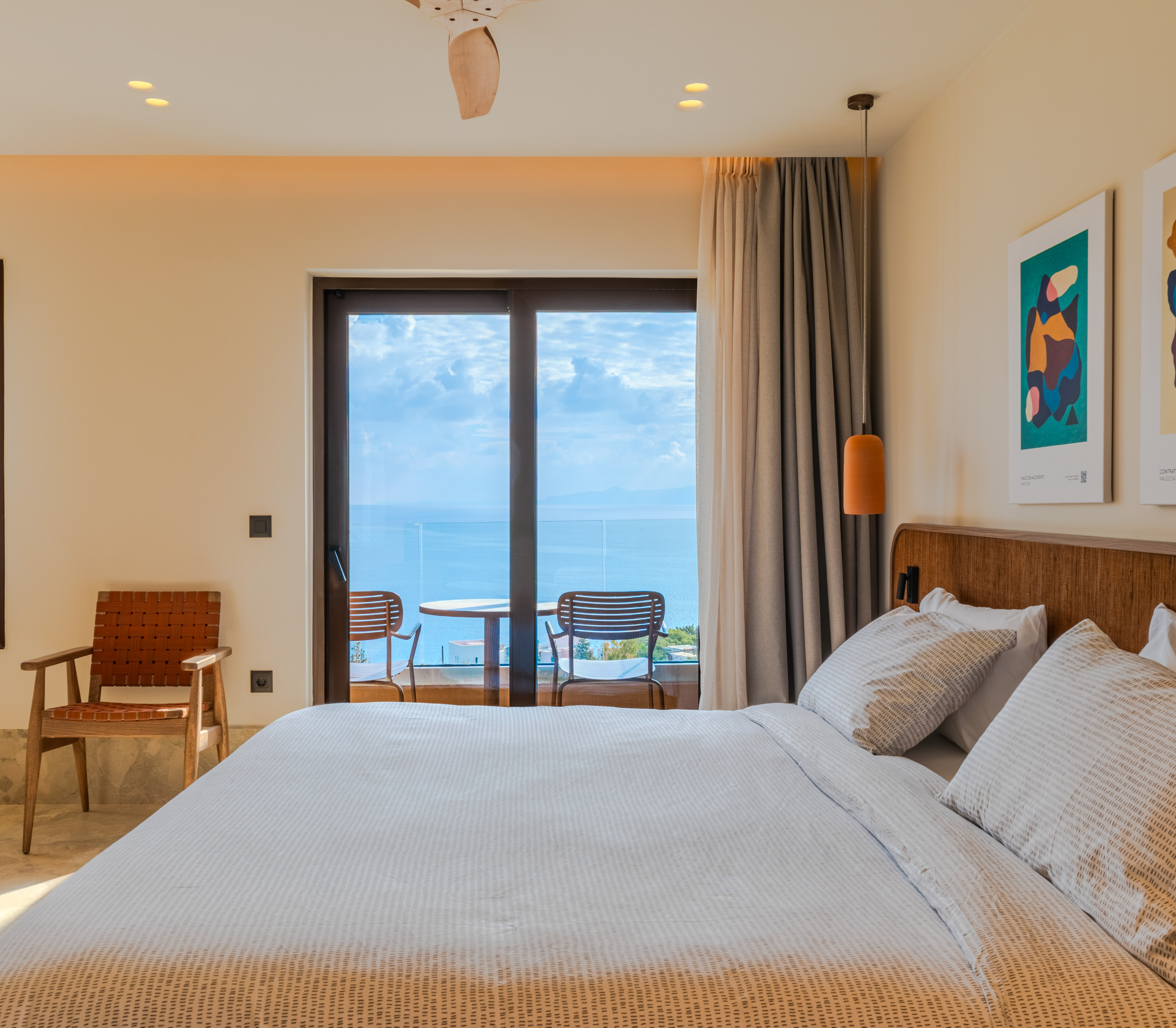 Modern hotel bedroom with sea view balcony and king bed.