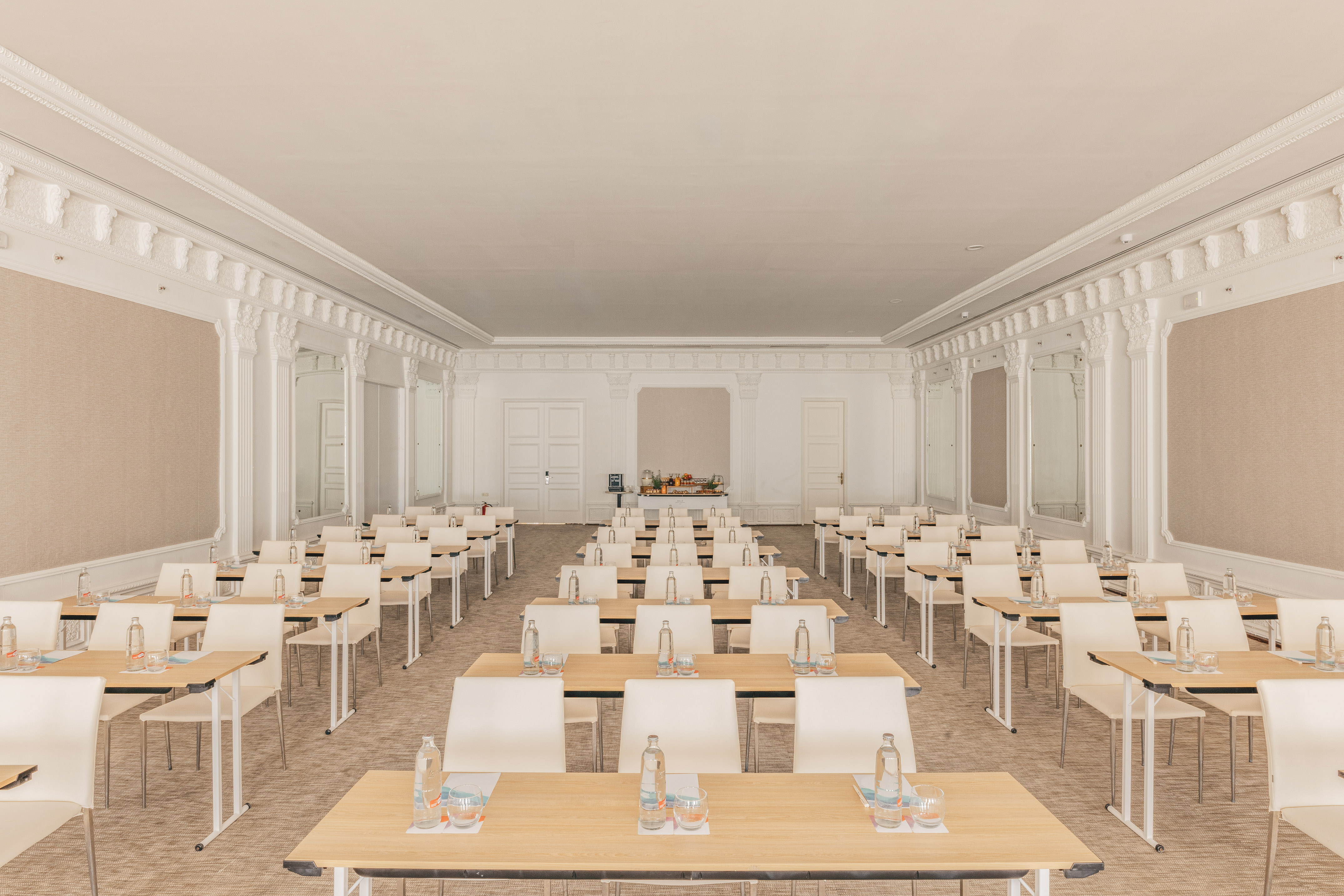 Elegant, empty conference room with rows of tables, chairs, and refreshments.