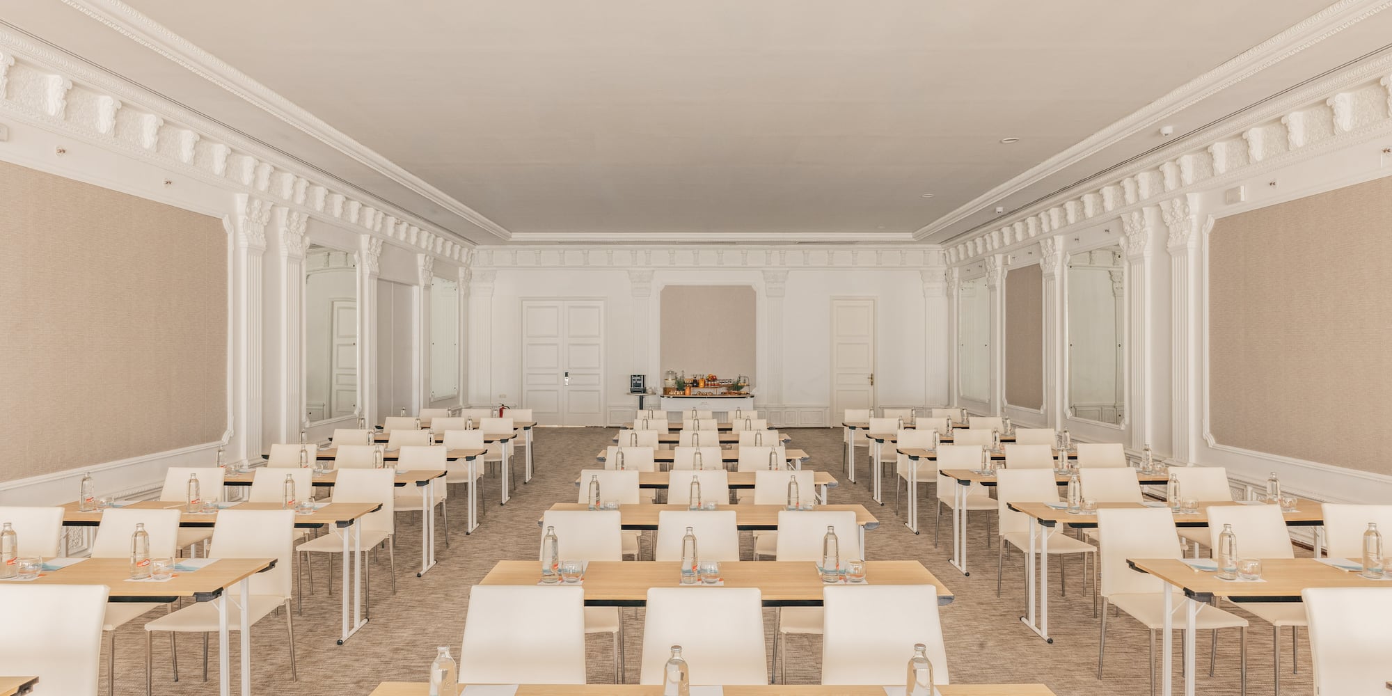Elegant, empty conference room with rows of tables, chairs, and refreshments.