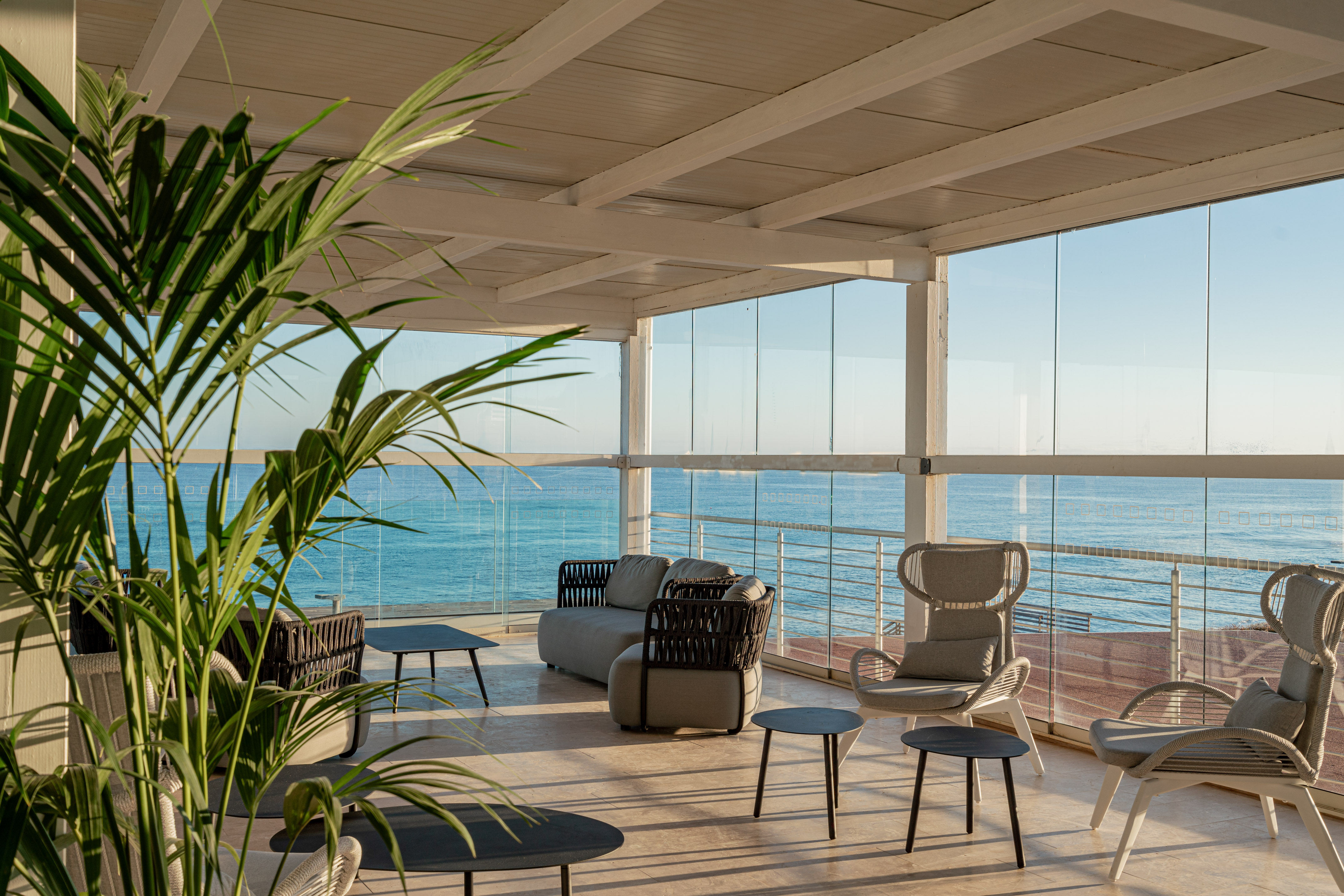 Modern oceanfront lounge with stylish outdoor furniture and glass walls.