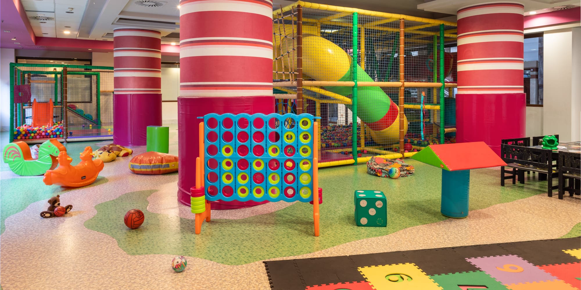 Colorful indoor children's soft play area with ball pit, slides, and games.