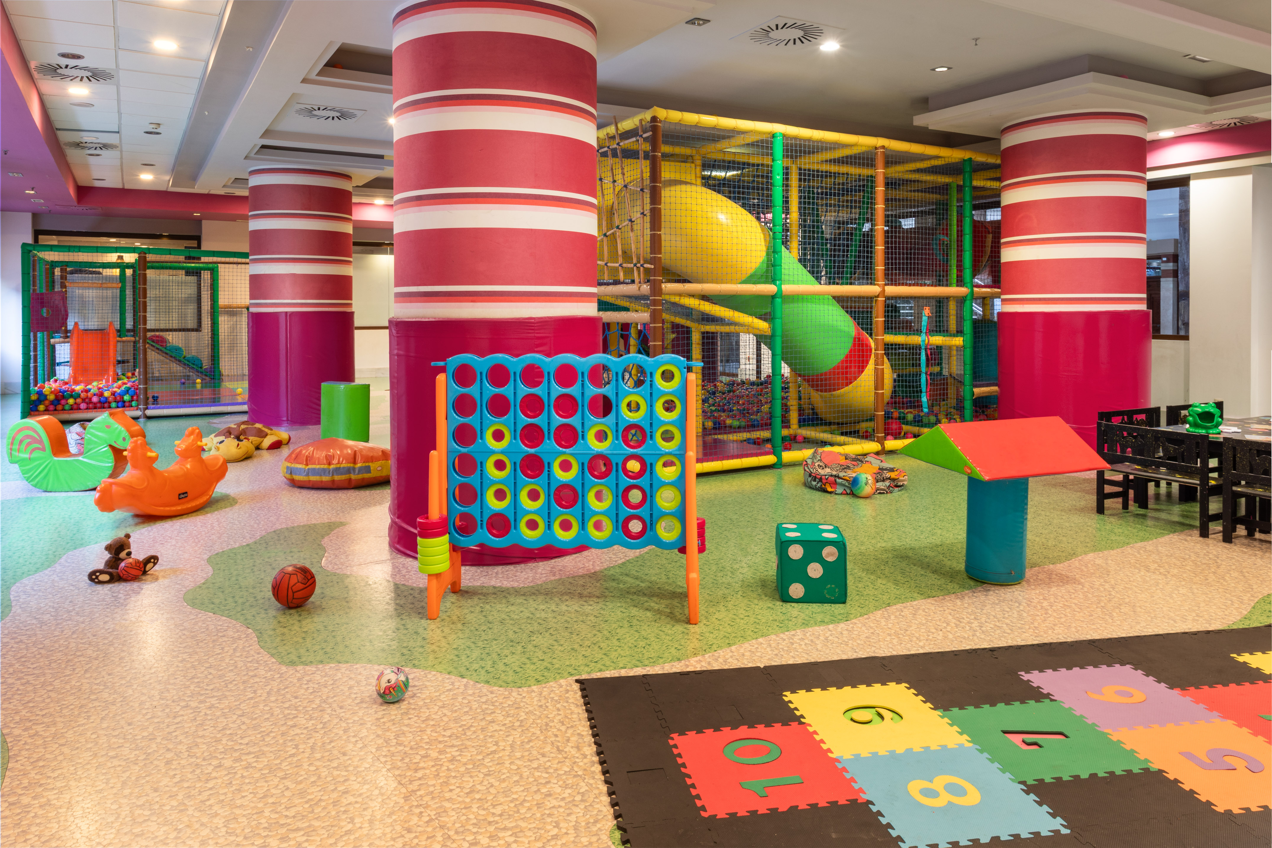 Colorful indoor children's soft play area with ball pit, slides, and games.