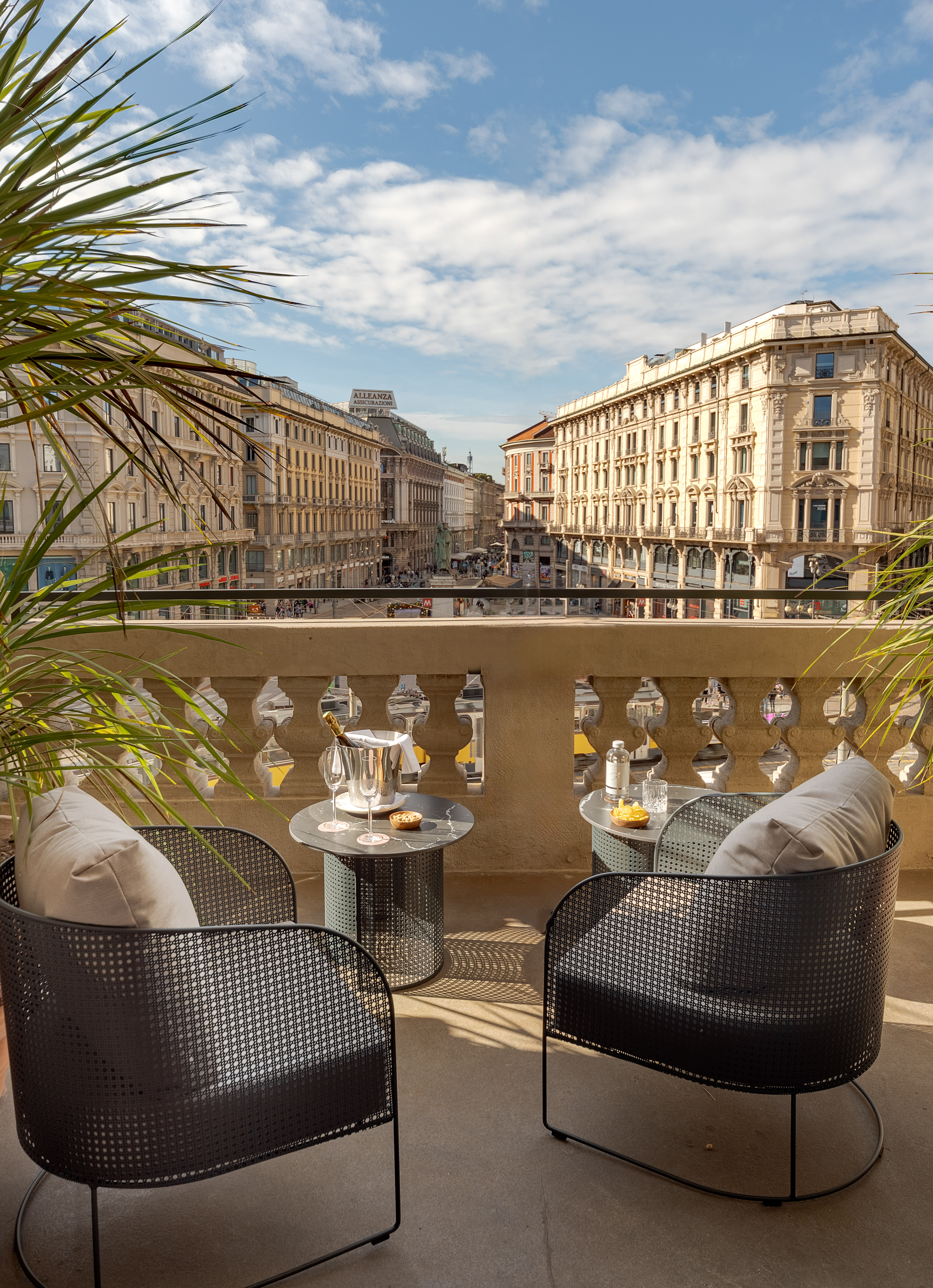 Elegant balcony with outdoor seating, champagne, and classic city street view.