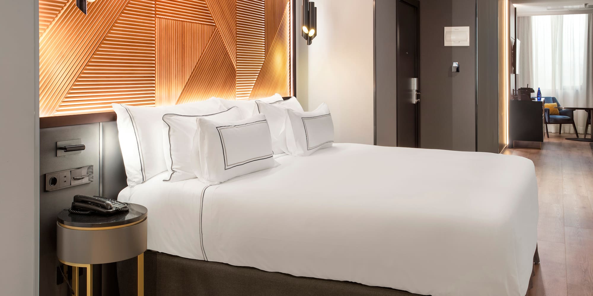 a bed with white sheets and a brown headboard