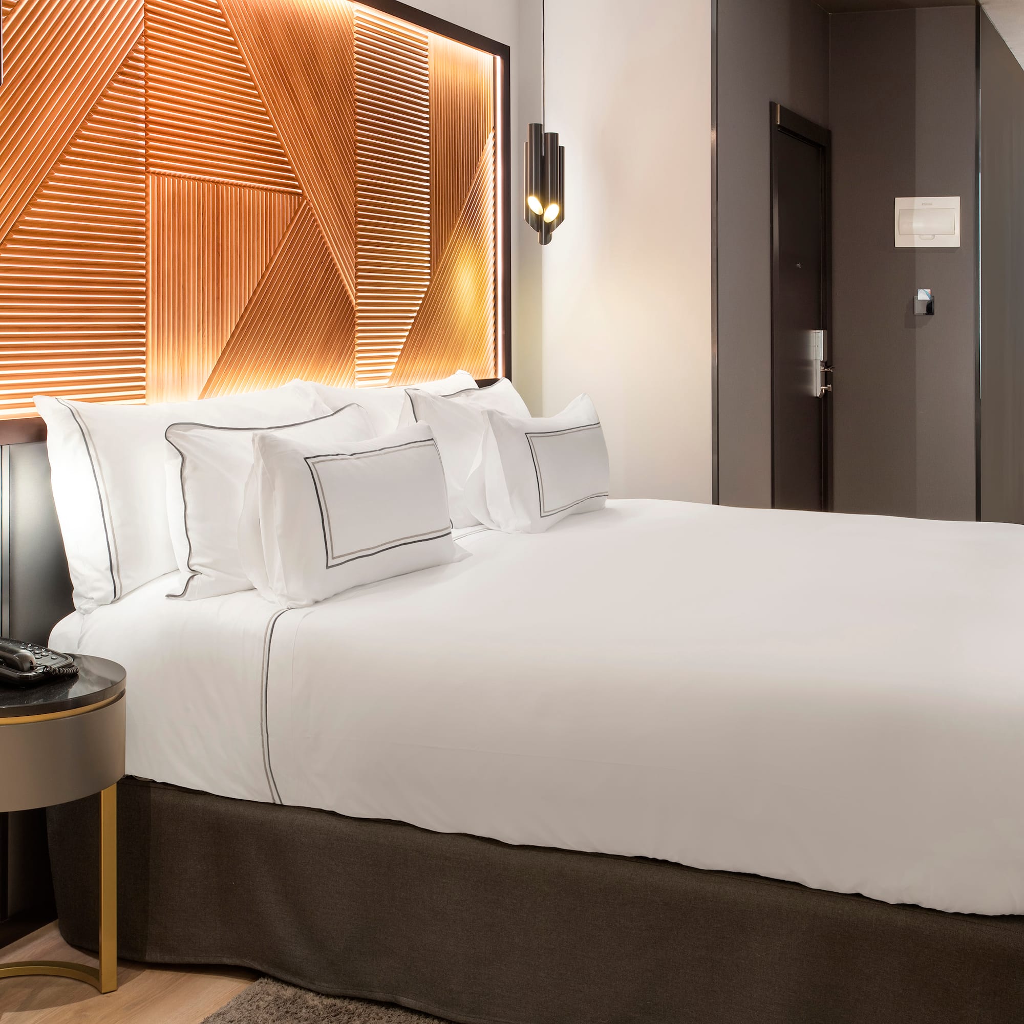 a bed with white sheets and a brown headboard