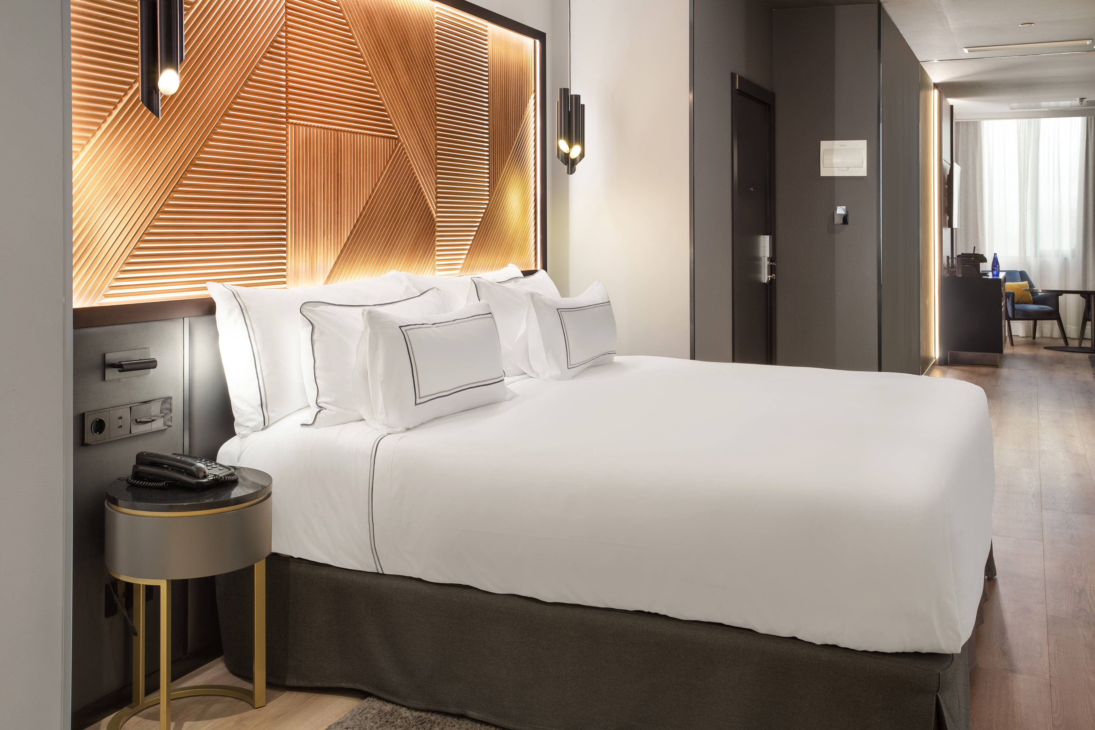 a bed with white sheets and a brown headboard