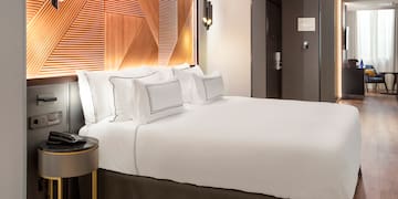 a bed with white sheets and a brown headboard