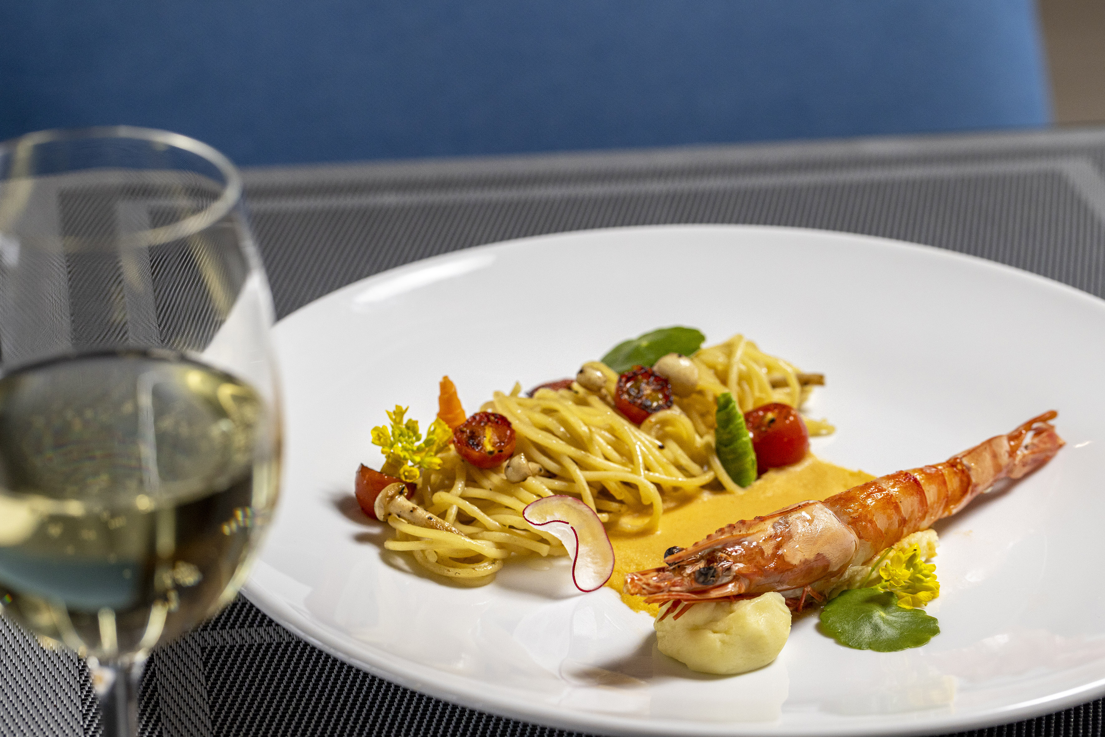 Fine dining prawn spaghetti with tomatoes, creamy sauce, and white wine.