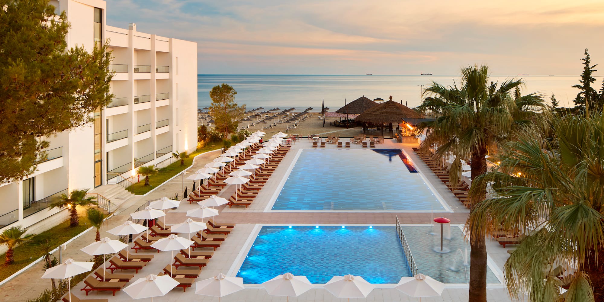 a pool with umbrellas and chairs and palm trees
