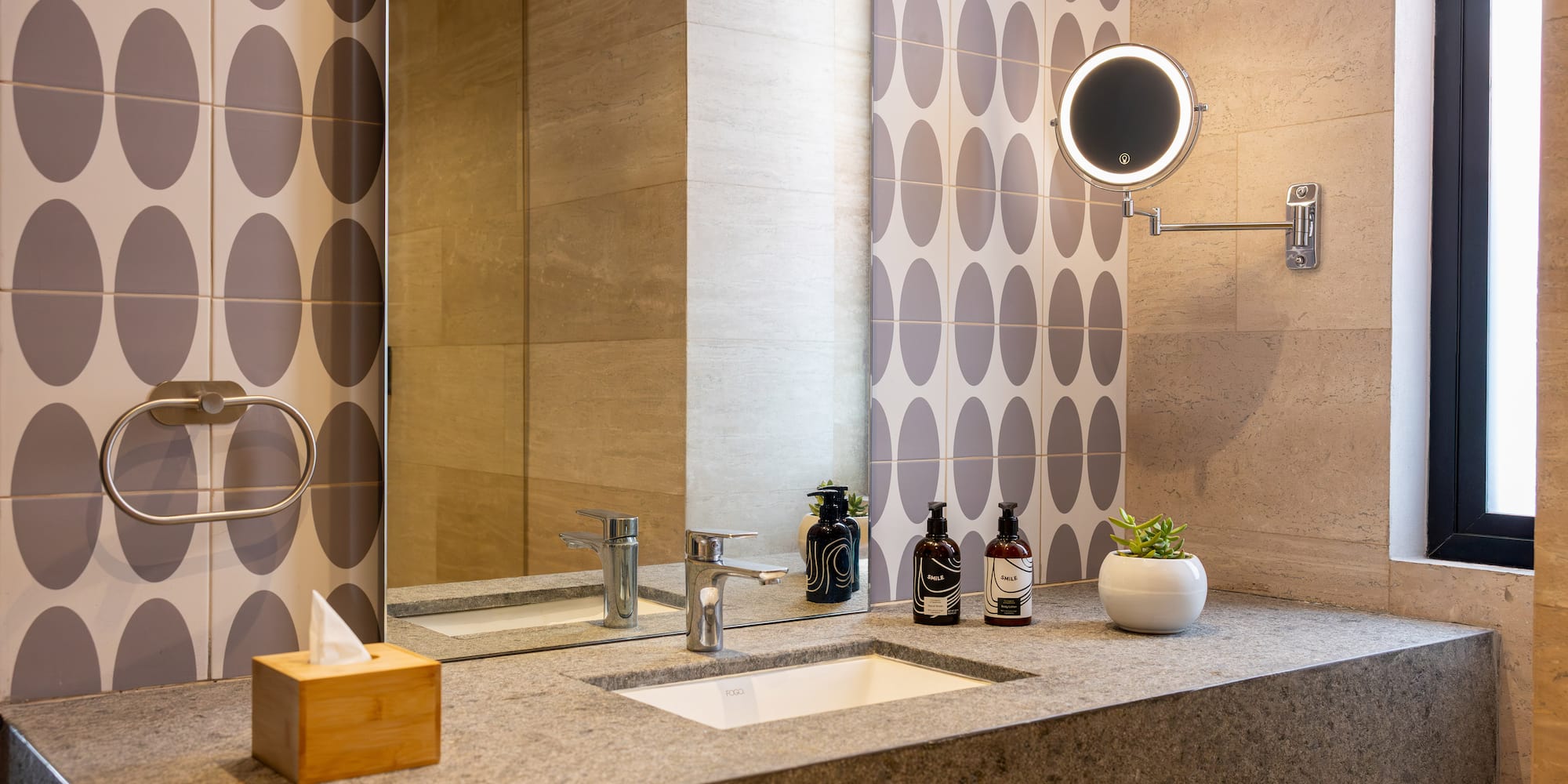 Modern bathroom vanity with stone countertop, integrated sink, and illuminated mirror.