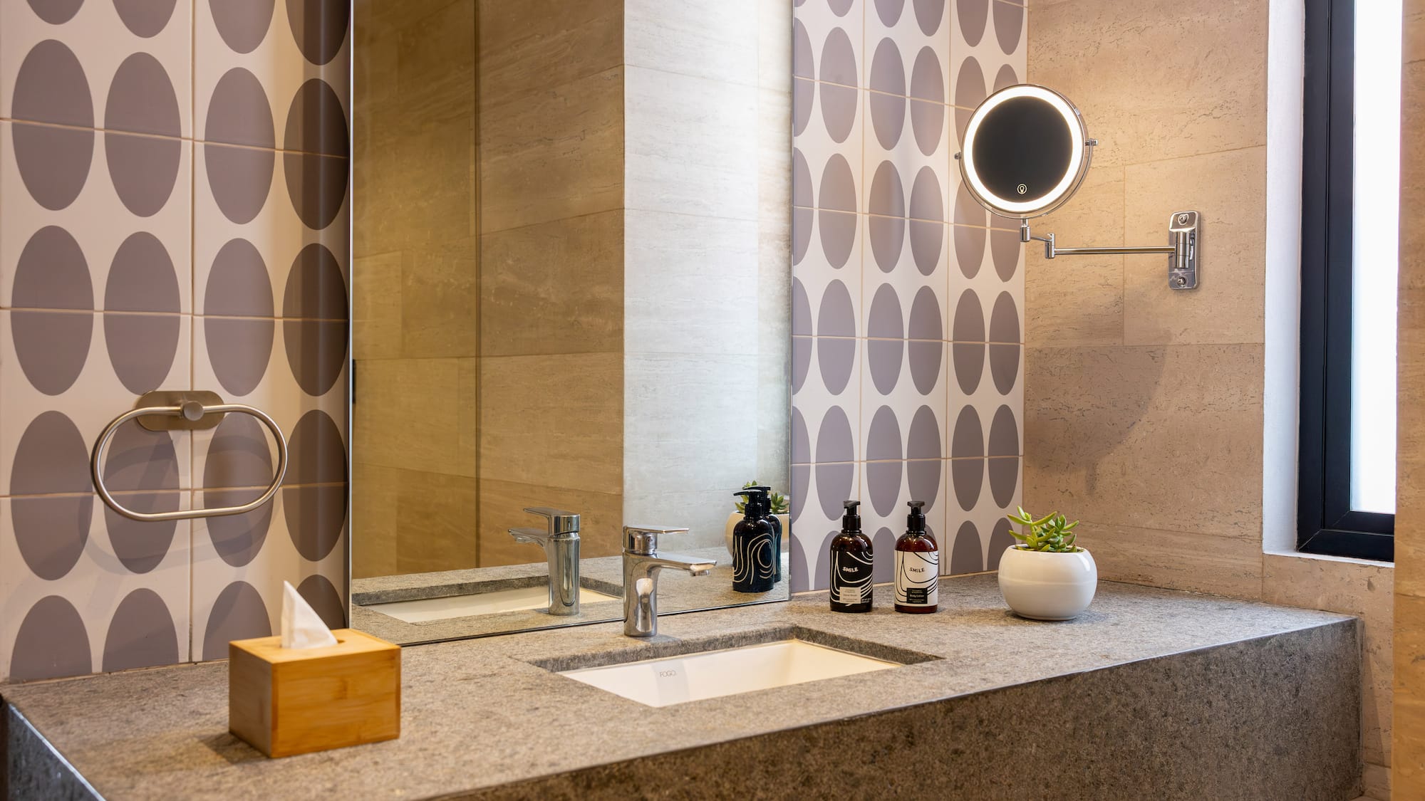 Modern bathroom vanity with stone countertop, integrated sink, and illuminated mirror.