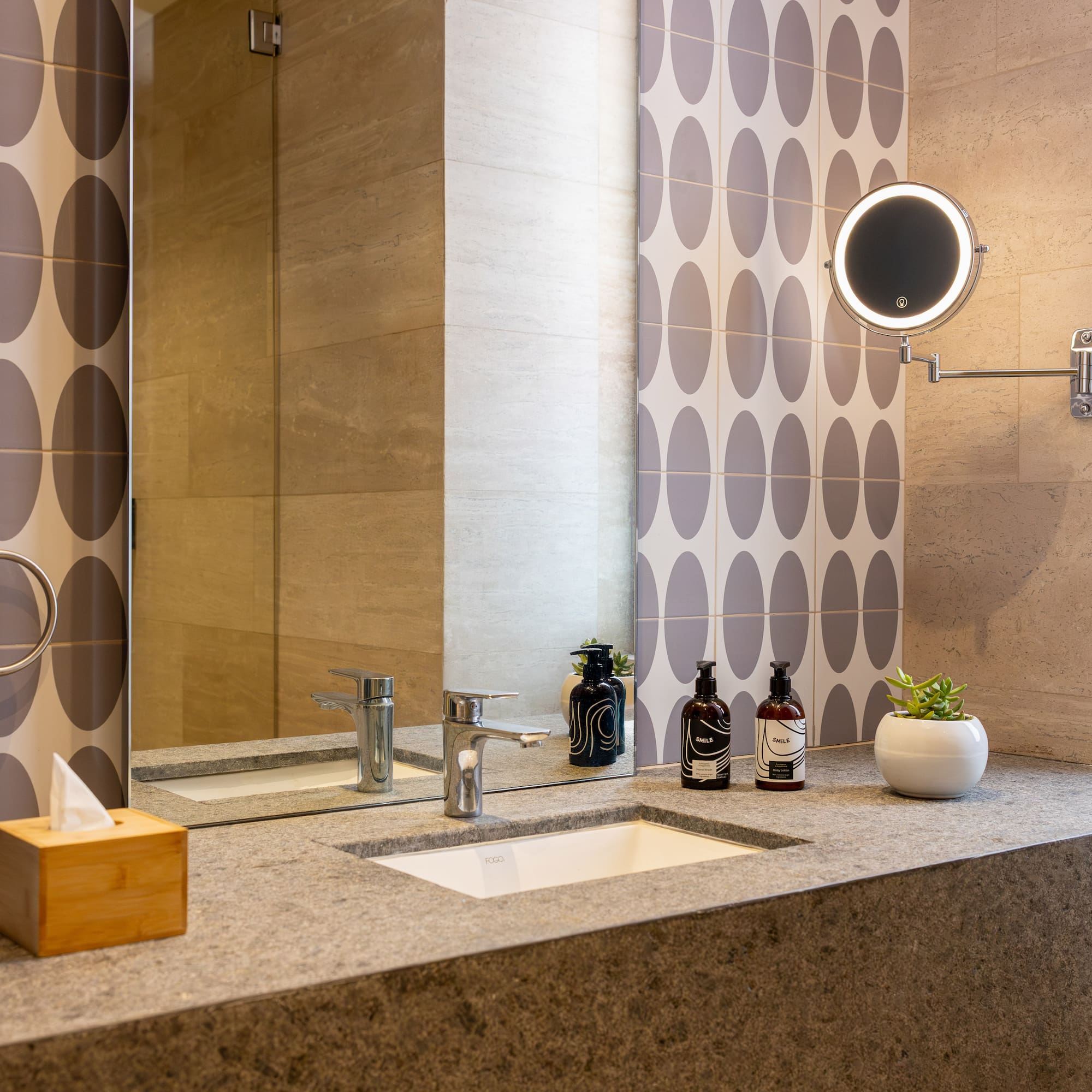 Modern bathroom vanity with stone countertop, integrated sink, and illuminated mirror.