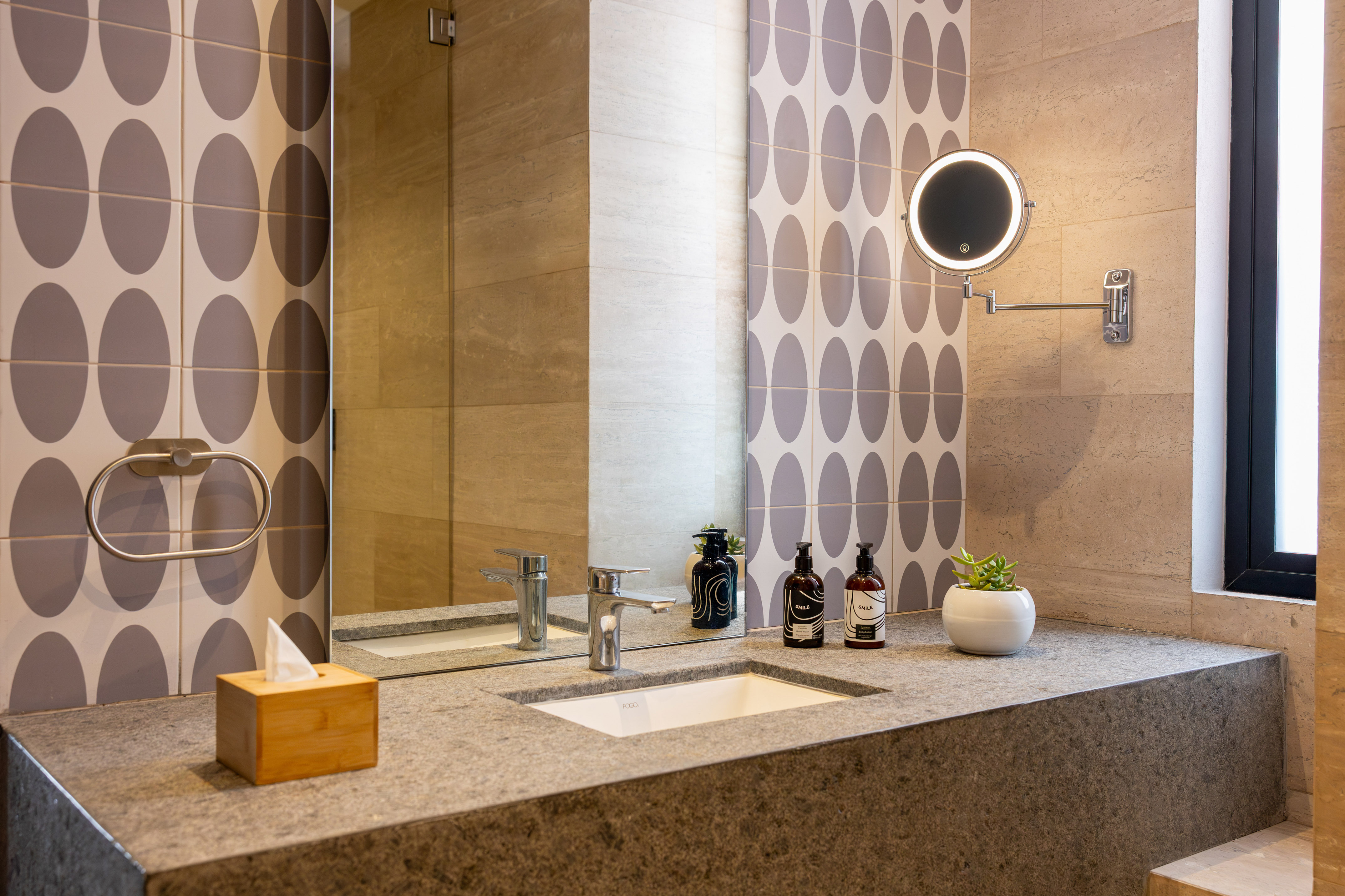 Modern bathroom vanity with stone countertop, integrated sink, and illuminated mirror.