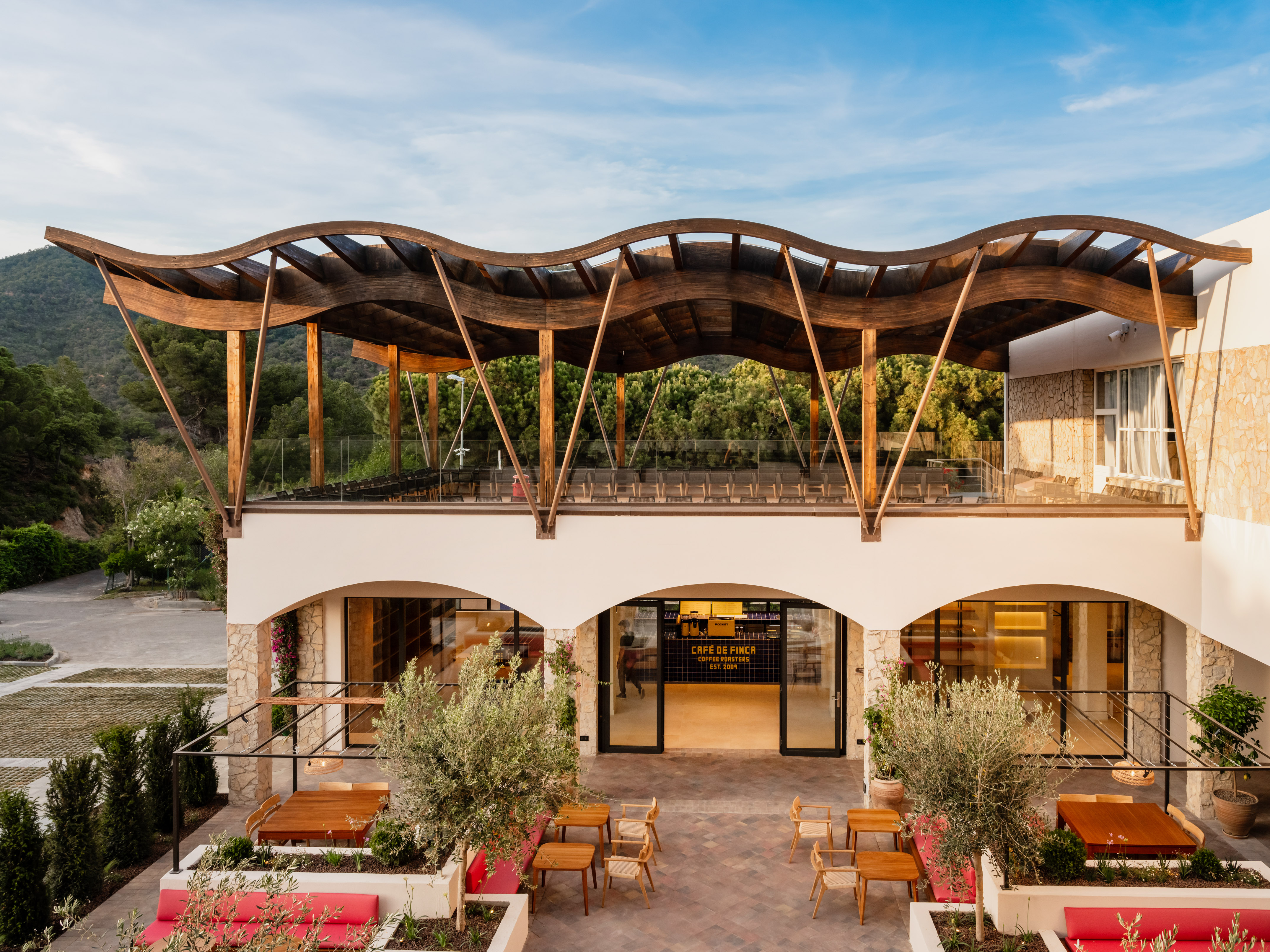 Cafe de Finca outdoor terrace with wavy wooden roof and modern architecture.