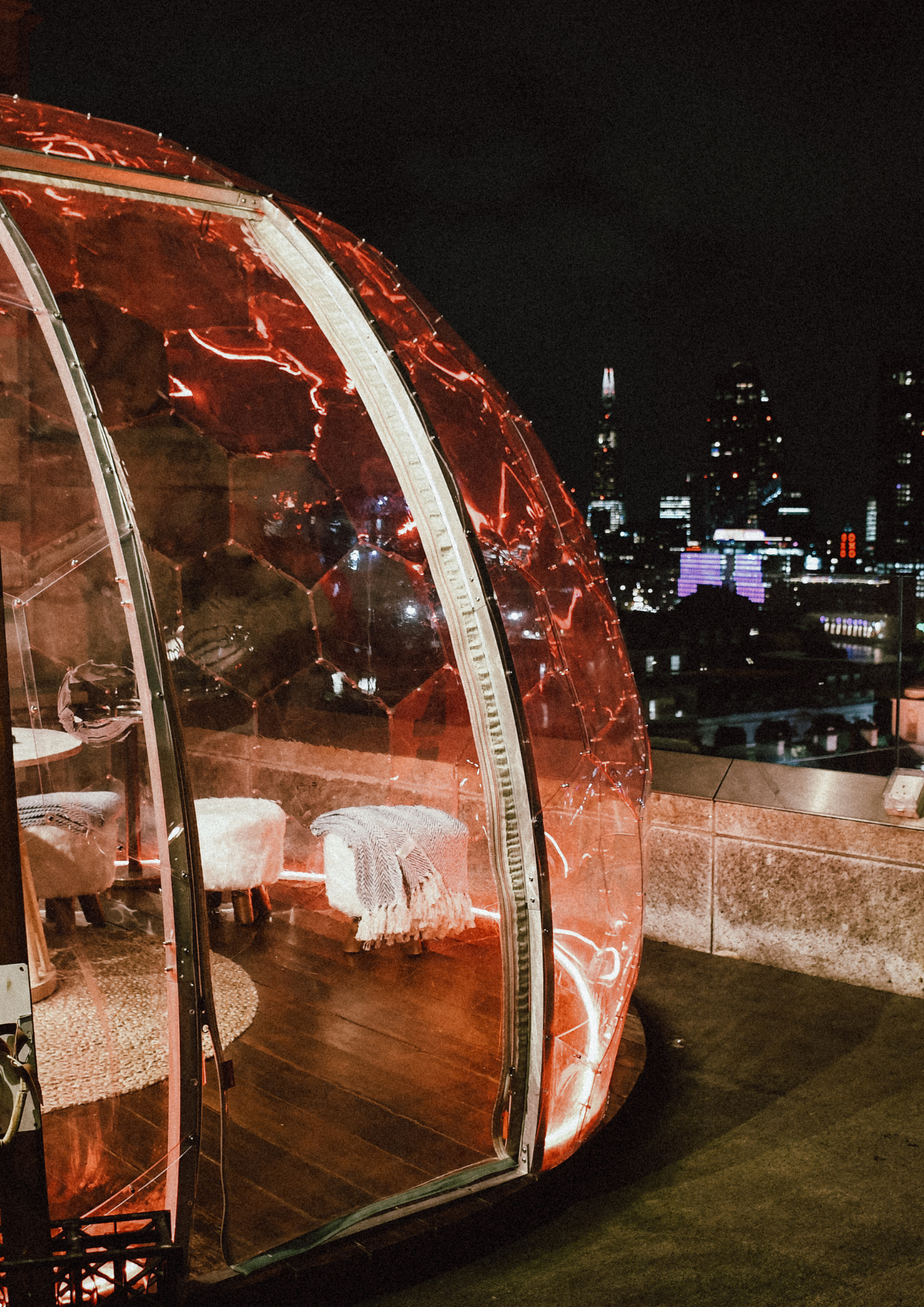 A glass dome sits on a rooftop, featuring a table and chairs inside.