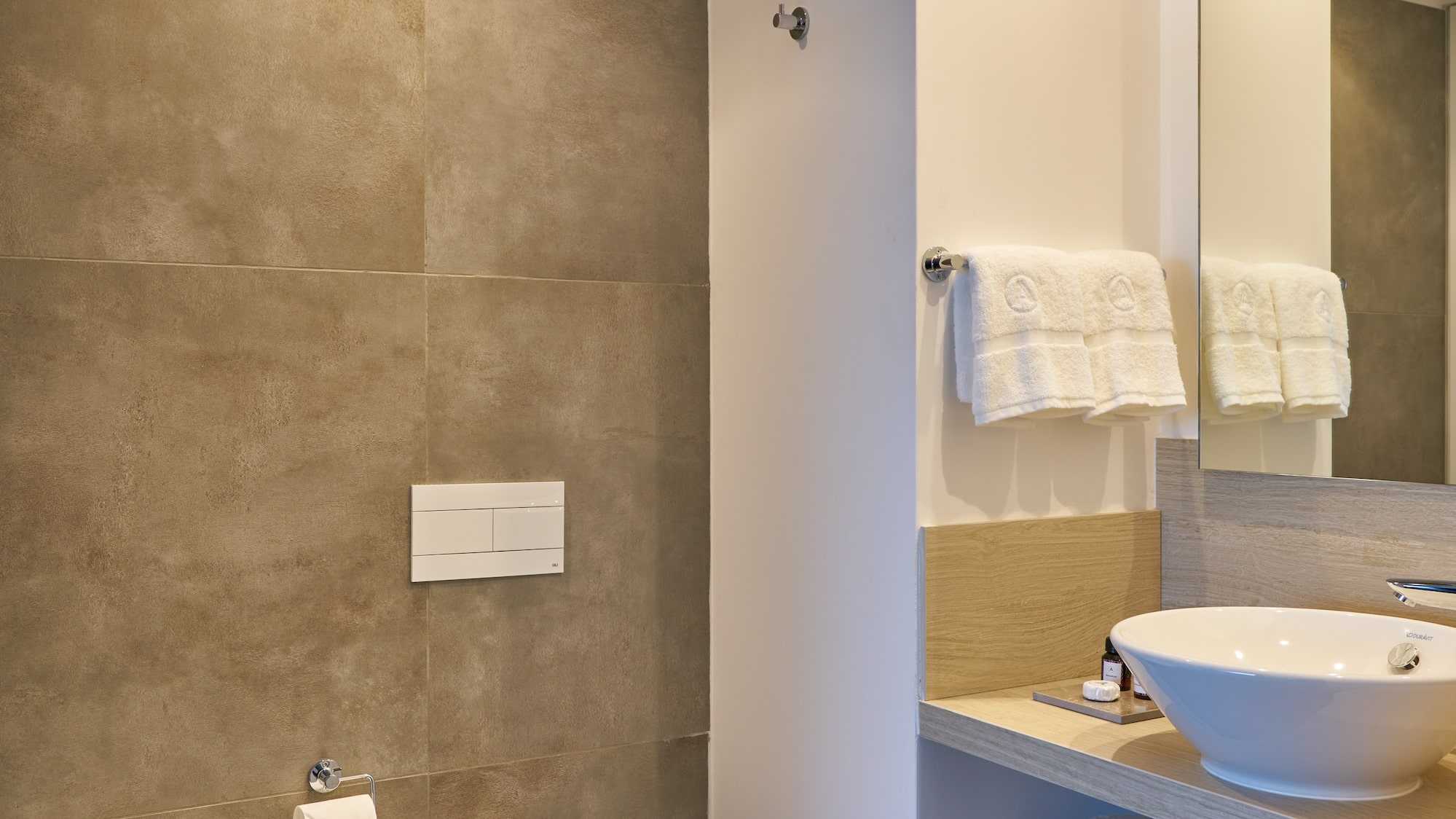 Stylish modern bathroom with toilet, bidet, vessel sink, and gray tiled walls.