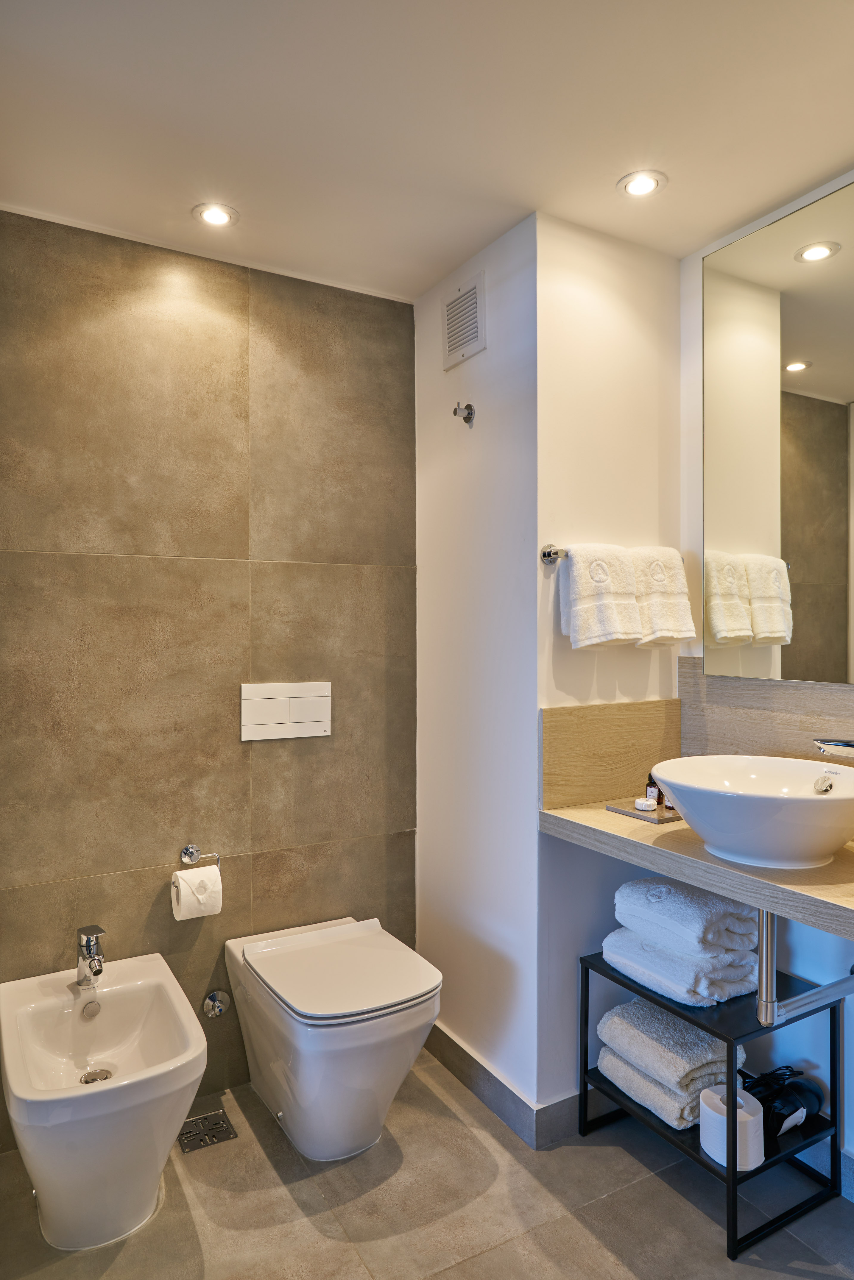 Modern bathroom with bidet, toilet, vessel sink, and large mirror.