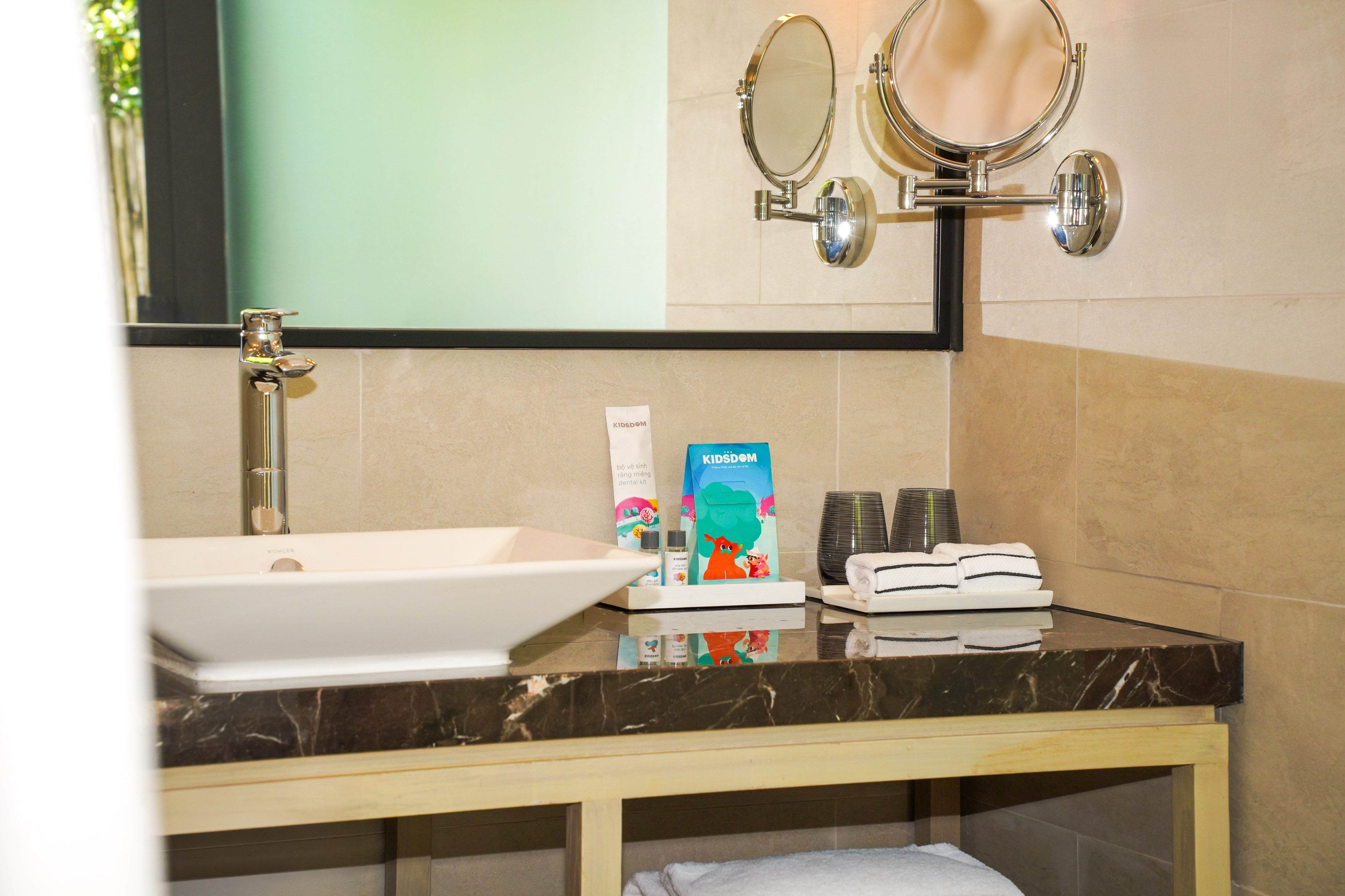 Bathroom vanity with sink, marble counter, mirrors, and kids' toiletries.