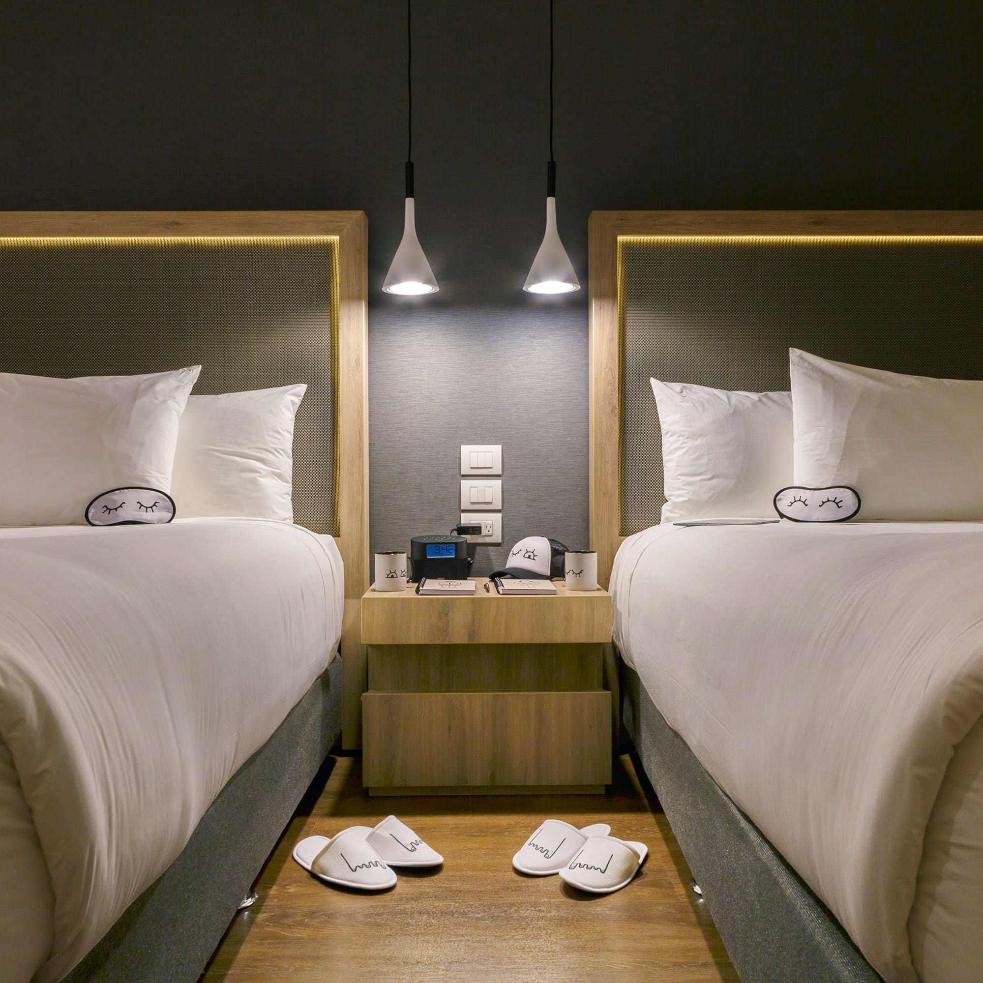 two beds with pillows and slippers on the floor